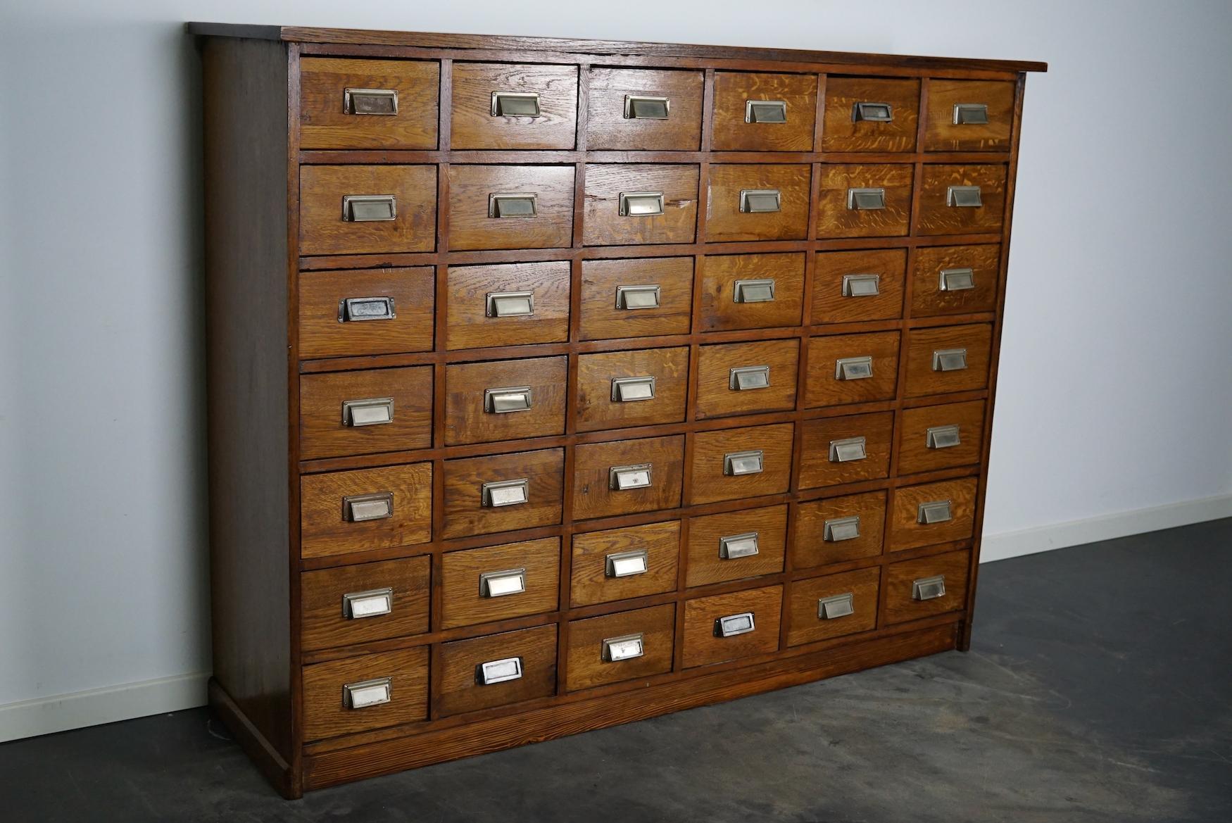 This apothecary cabinet was made circa 1950s in Germany. It features 42 decent sized drawers with metal handles. The interior dimensions of the drawers are: D W H 38 x 21 x 13 cm.