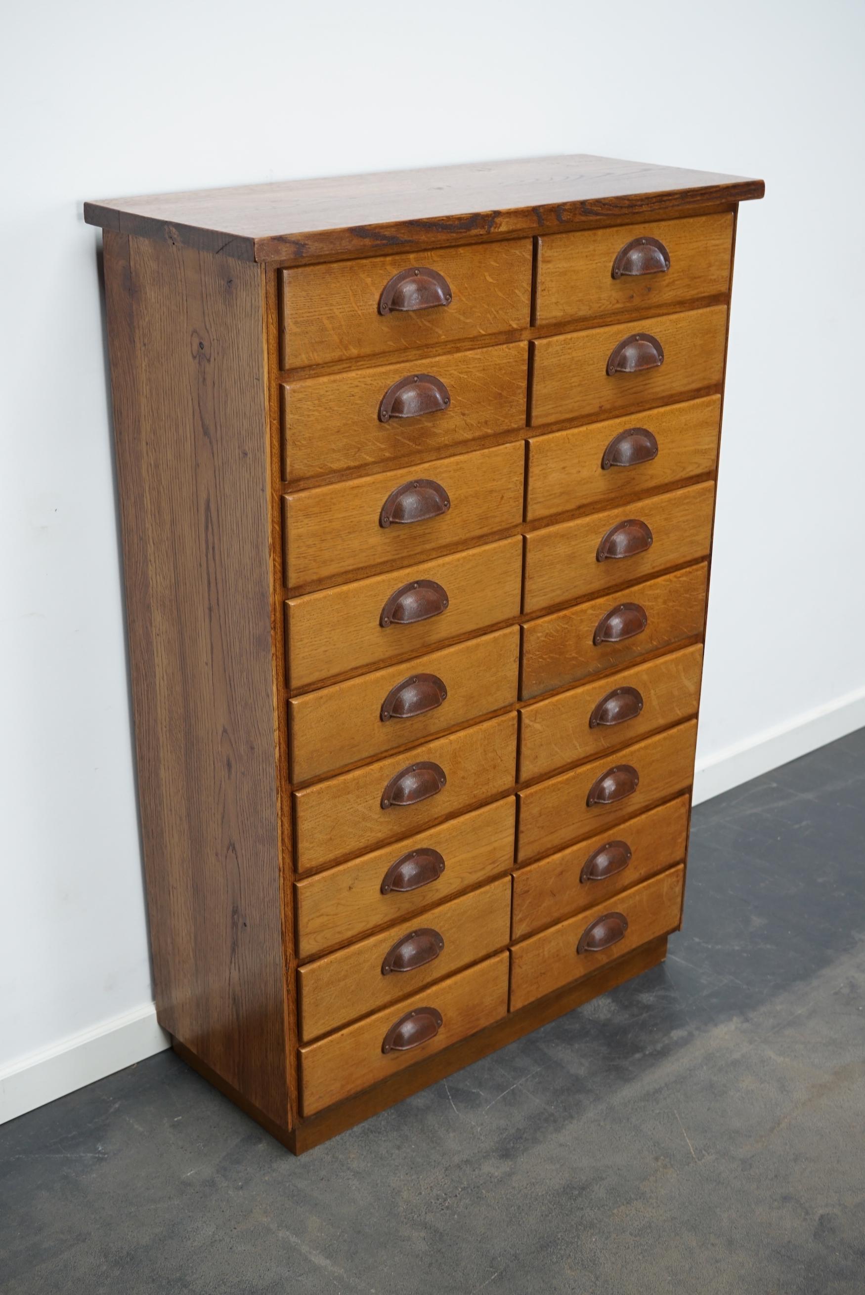 This apothecary cabinet was made from oak circa 1940 / 1950s in Germany. It features 18 drawers with nice metal handles. The interior dimensions of the drawers are: D W H 24 x 27 x 7 cm.