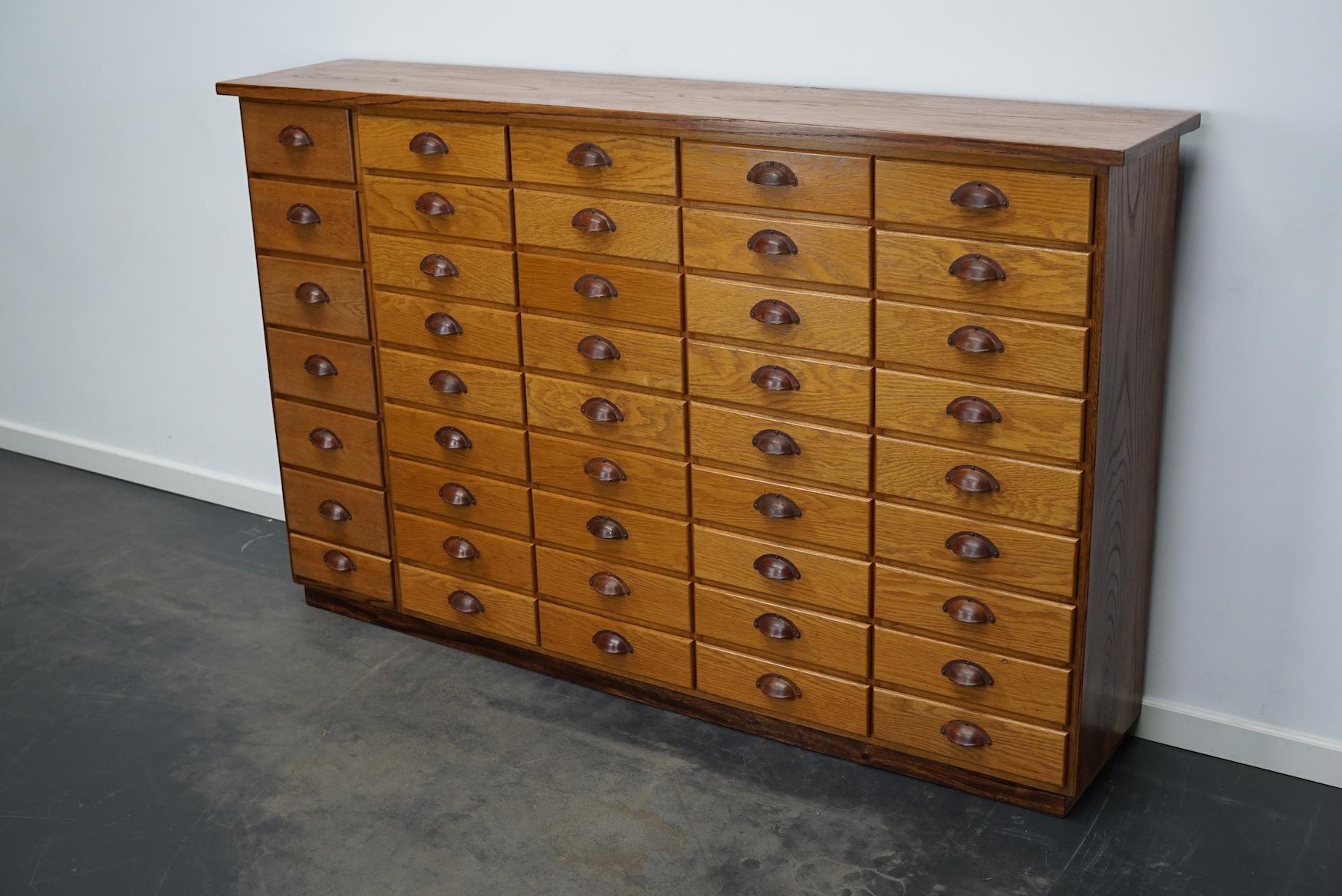 This apothecary cabinet was made from oak circa 1940 / 1950s in Germany. It features 43 drawers with nice metal handles. The interior dimensions of the drawers are: DWH 26 x 27 x 7 cm and 26 x 22 x 10 cm.