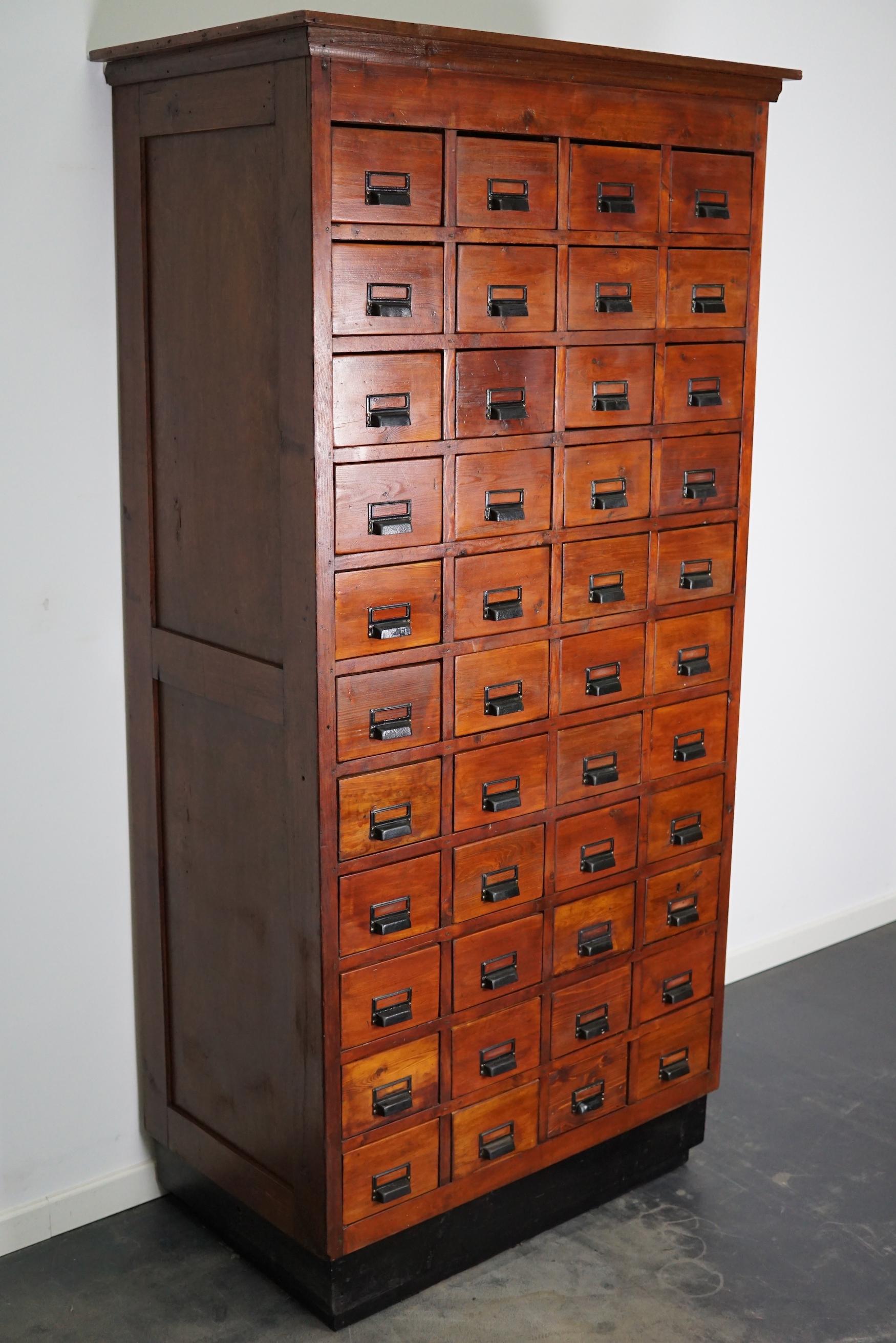 This apothecary cabinet was made circa 1950s in Germany. It features 44 drawers with nice black metal handles. It is made from pine and it remains in a good condition. The interior dimensions of the drawers are: D x W x H: 38 x 16 x 7 / 11 cm.