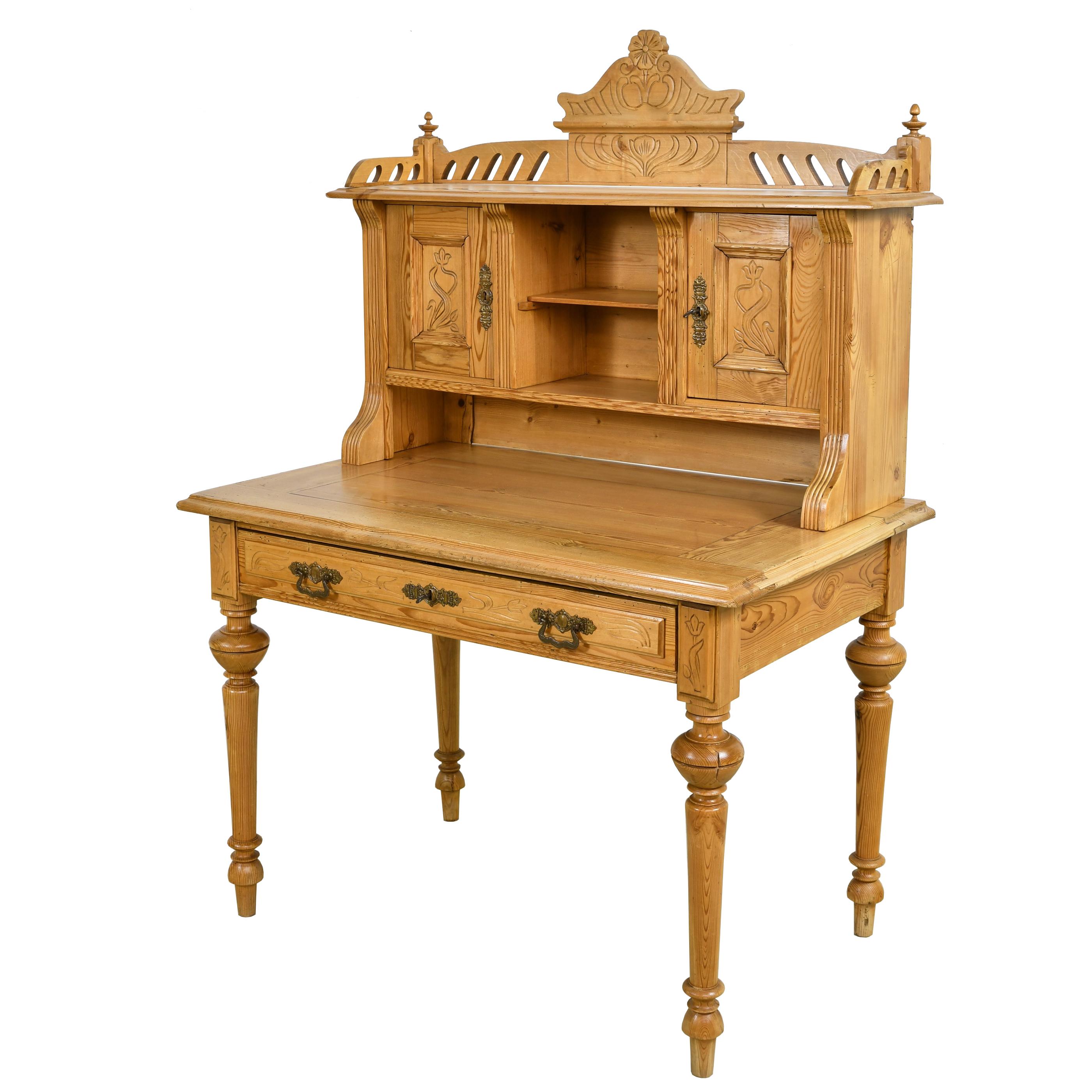 A lovely and well-crafted Jugendstil desk in pine with upper cabinet resting over a writing table offering open shelving & closed storage. Top has a carved bonnet with stylized flowers and open carvings with turned finials on the corners. Writing