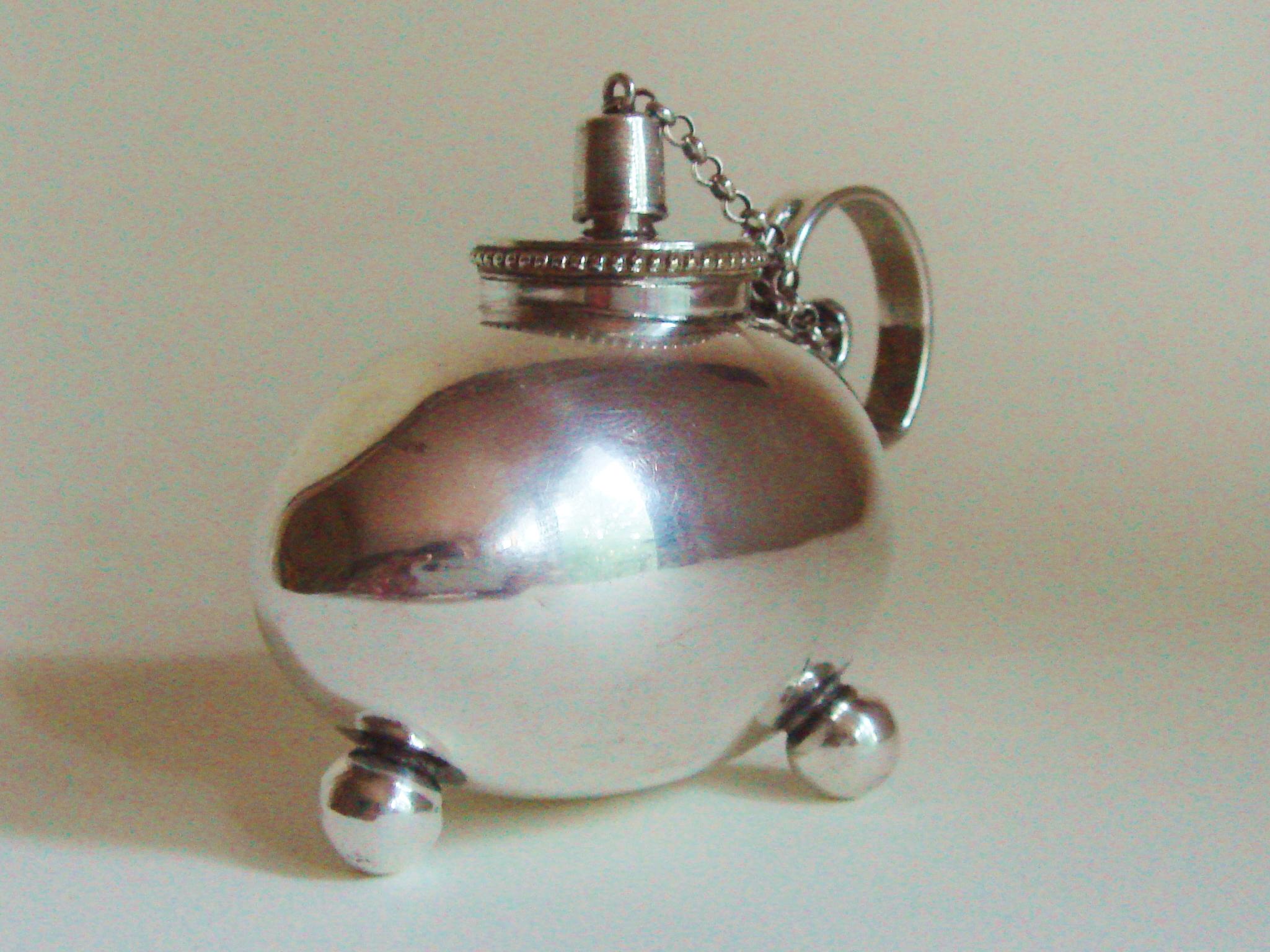 This wonderful silver plated German Jugendstil oil lamp/table cigar lighter is in the shape of an egg and stands on three spherical feet. It has a chamber-stick type handle presumably for passing the lighter round among the assembled gentlemen when
