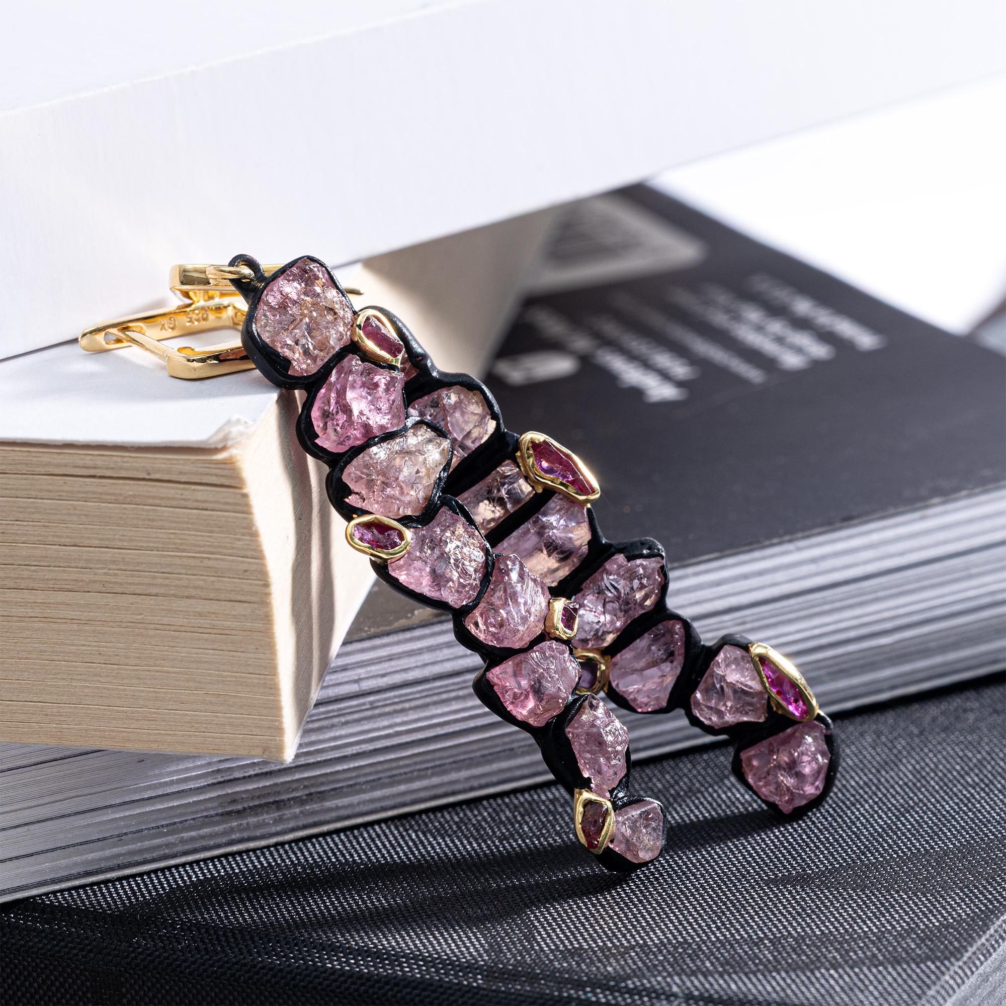 Danae non segue uno schema: gli orecchini crescono nella loro direzione. Una sottile linea verticale contiene zaffiri rosa grezzi, mentre i rubini grezzi appaiono lungo la linea in modo naturalmente irregolare, come se le pietre decidessero dove