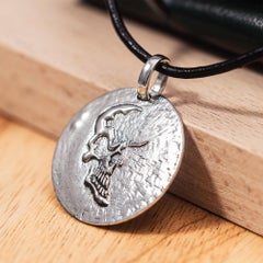 Pendentif rond en argent 925 oxydé « Kabirski Dhara » (Allemagne), avec un relief représentant la moitié d'un crâne