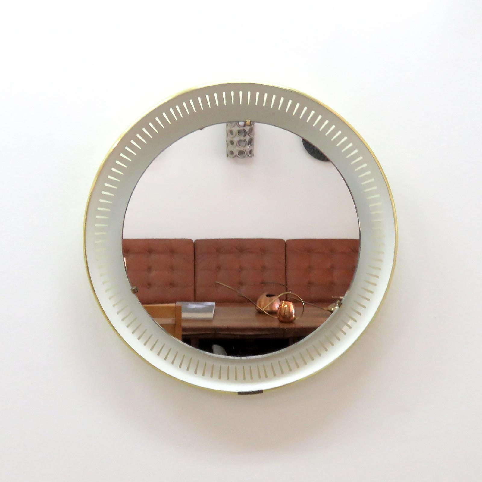 magnifique miroir rond éclairé par Ernest Igl pour Hillebrand, Allemagne, 1960, rétro-éclairé par un jeu de trois ampoules, miroir flottant sur un support en métal émaillé perforé avec des accents en laiton, le dos du miroir est émaillé dans un,