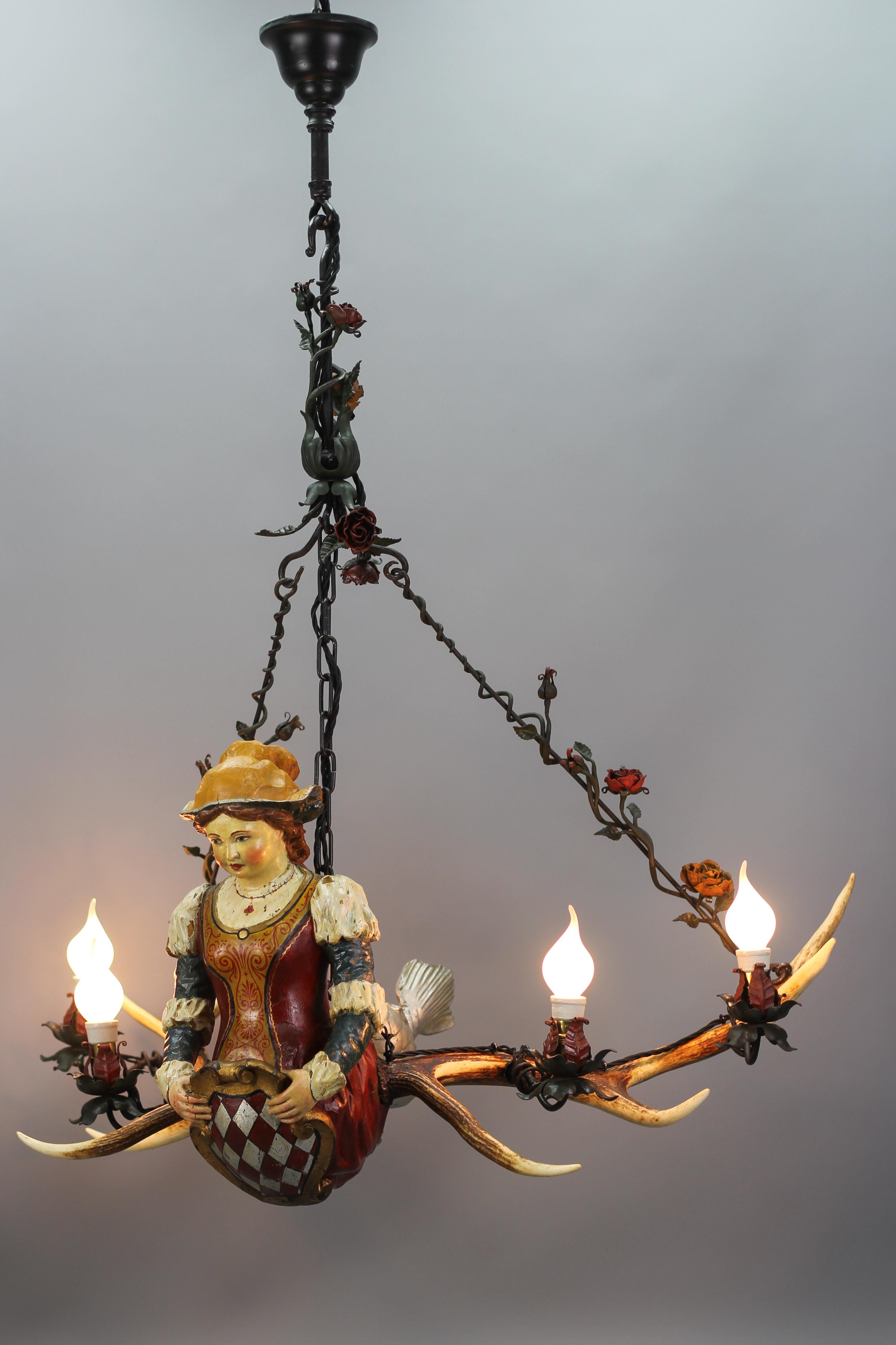 This amazing German chandelier features a delicate hand-carved and polychrome hand-painted mythical lady or mermaid with a scaly fishtail. The adorable and handsome lady is holding a cartouche-shaped shield. 
The light fixture is hung on a chain