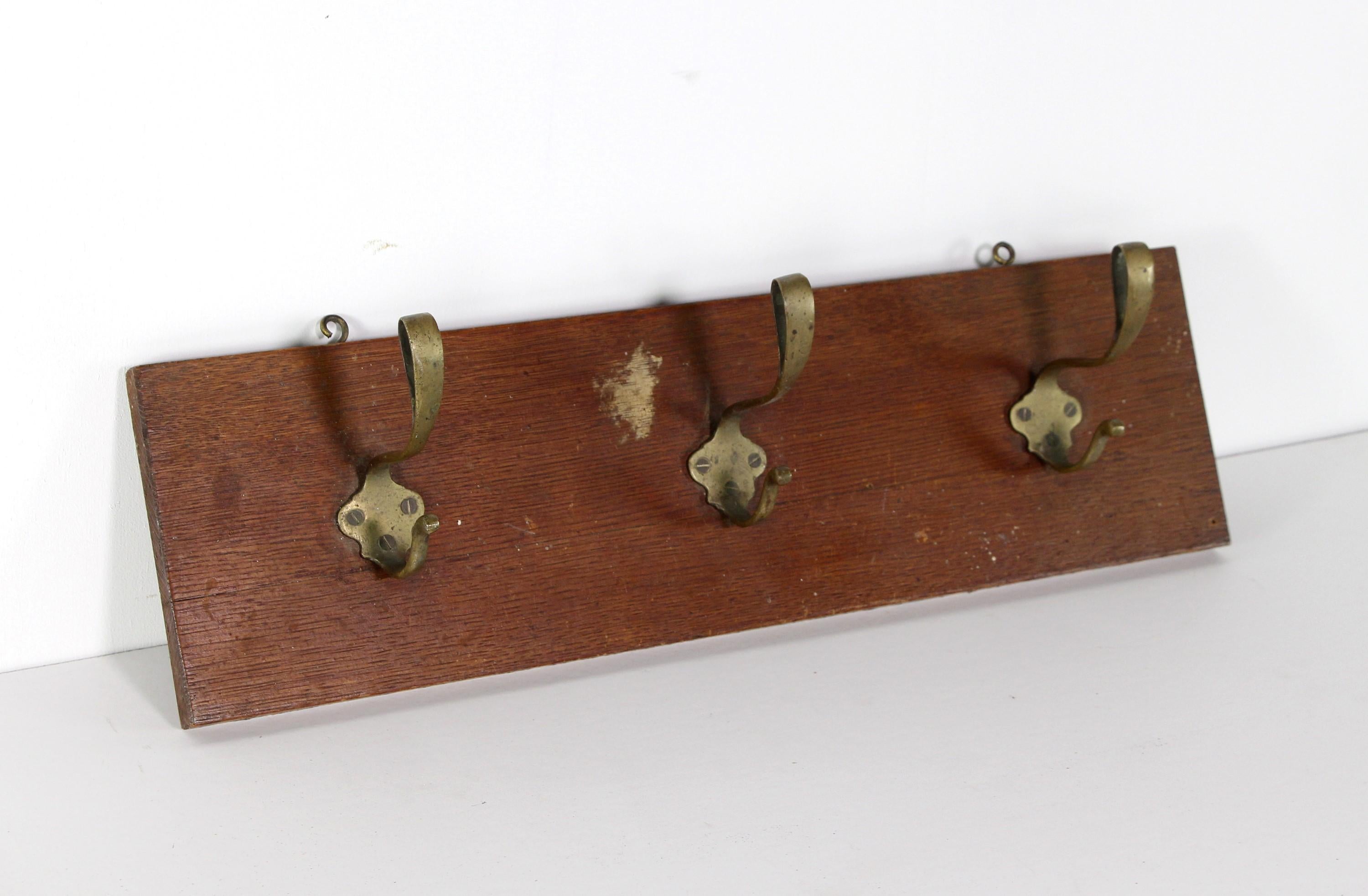 Mid-Century Modern design coat rack featuring three Jugenschtil brass hooks mounted on a dark tone wood plank. Please note, this item is located in our Scranton, PA location.