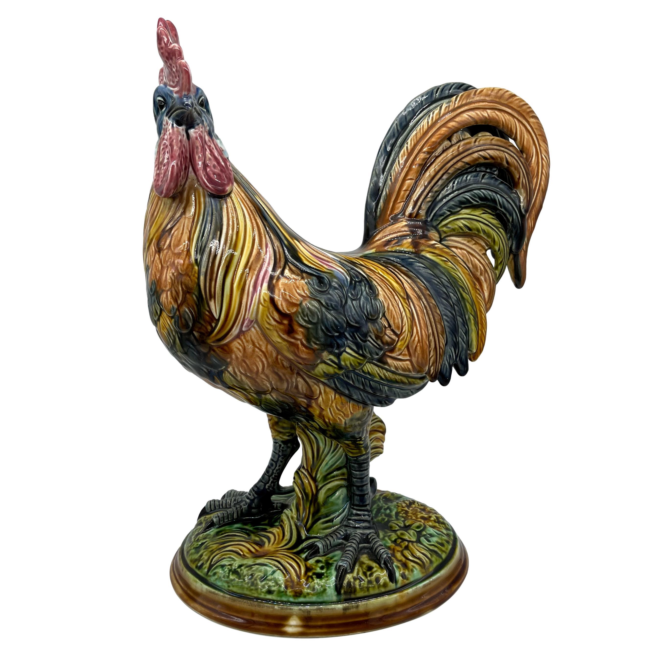 Majolica Figural Rooster, naturalistically modeled as an alert cockerel, the feathers with mottled gold, brown and blue glazes, the comb and wattle glazed in pink and red, on an oval pedestal base, the reverse with painted mark: Steingutfabrik D.&F.