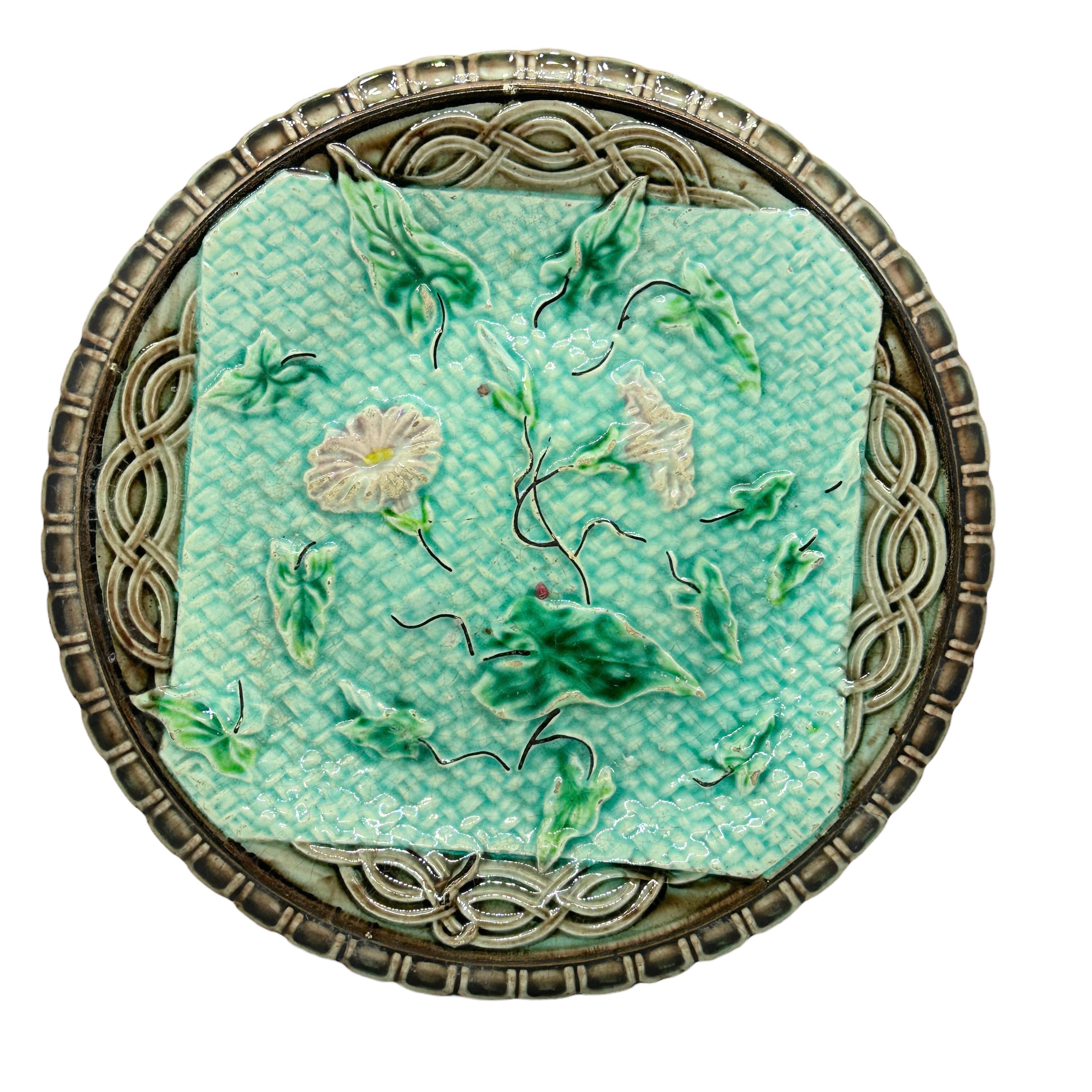 Early 20th century German majolica plate with morning glory on a blue basket weave and a brown border, circa 1900. Small cracks in the glazing, glazing craquelure, chip at the backside. Nice addition to your table or just to display. Please see