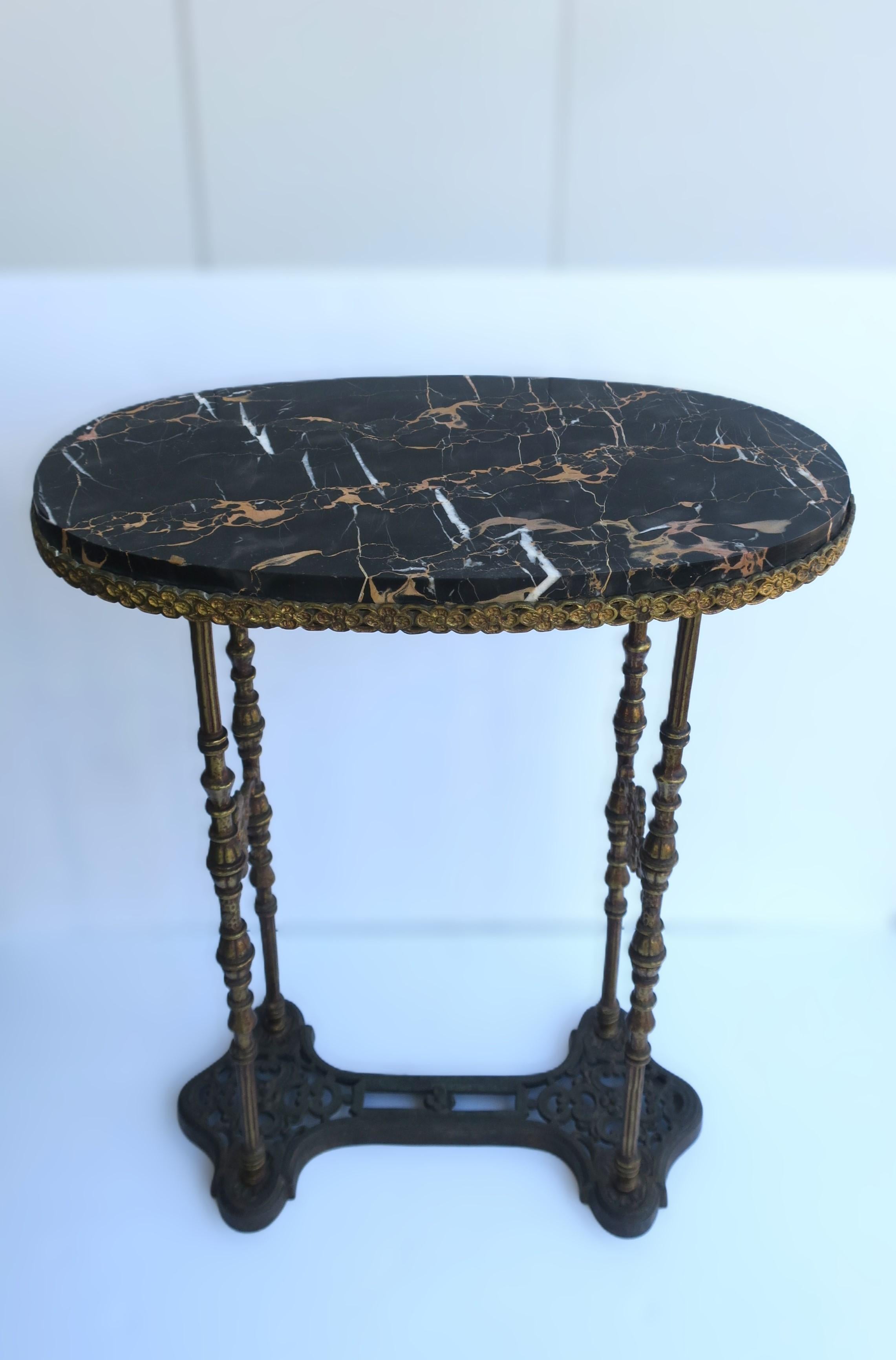 A substantial German oval marble console table with a black 'Porto' marble top and gold gilt brass or bronze base, circa early-20th century, Germany. Table has an oval marble top embraced by a gold gilt frame. Marble top is attached to frame. Table