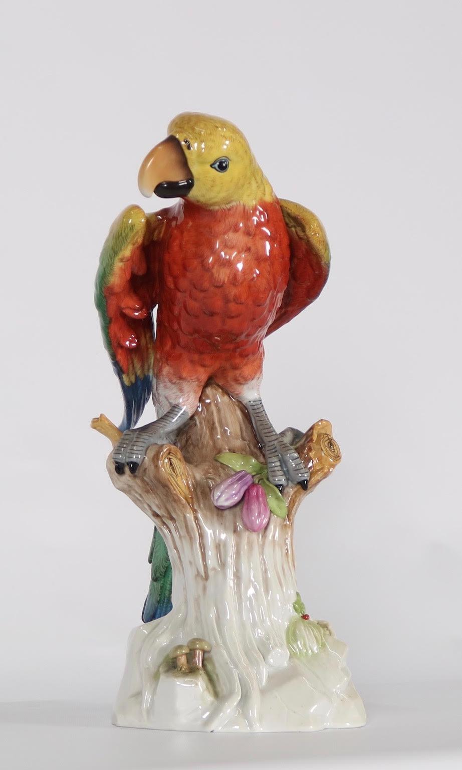 German Meissen style porcelain macaw parrot figurine sitting atop a fruit bearing tree stump. The style of this piece is strongly influenced by Kaendler’s animal figurines from the 18th century which were made for Meissen. The piece was hand-made in