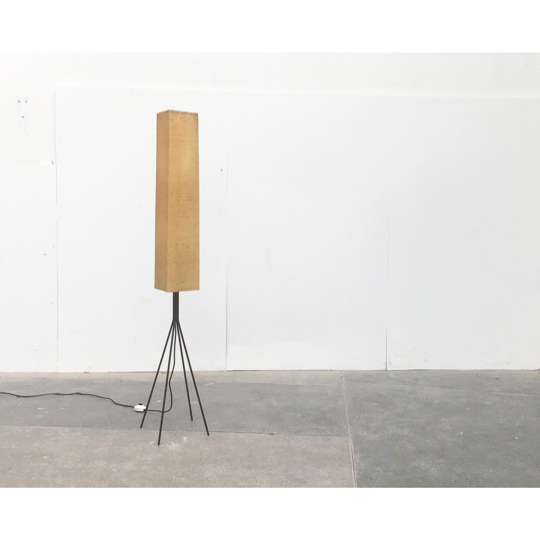 This is a mid-century floor lamp from the German manufacturer Hesse lights KG.

The filigree steel frame is painted black. Instead of a traditional tripod, this lamp is provided with four feet. The rectangular shield is structured from a type of