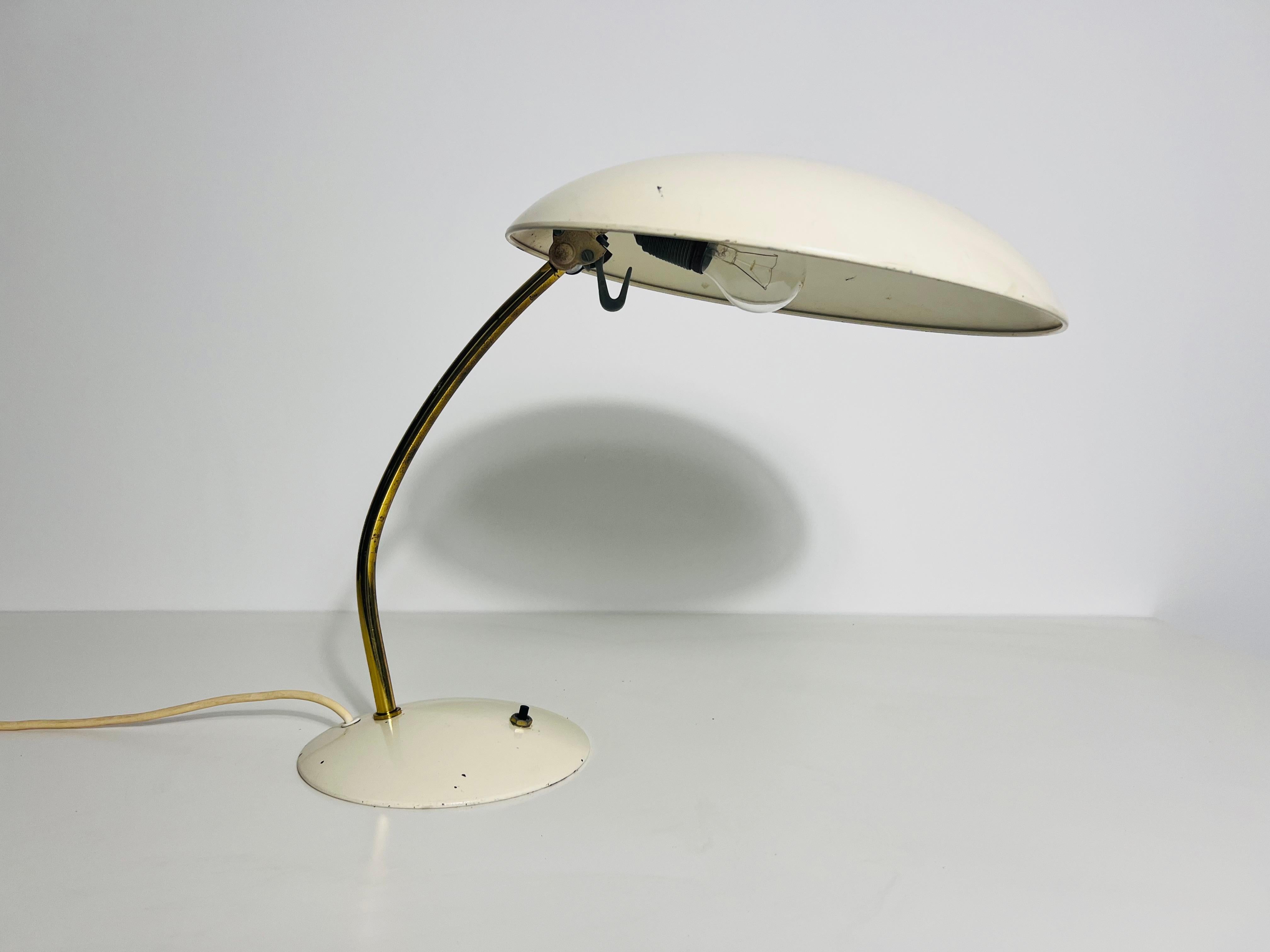 Cette lampe de table vintage, fabriquée en Allemagne dans les années 1960, est un exemple étonnant de design inspiré du Bauhaus. Dotée d'une élégante base métallique en laiton, cette lampe allie fonctionnalité et style intemporel. L'abat-jour