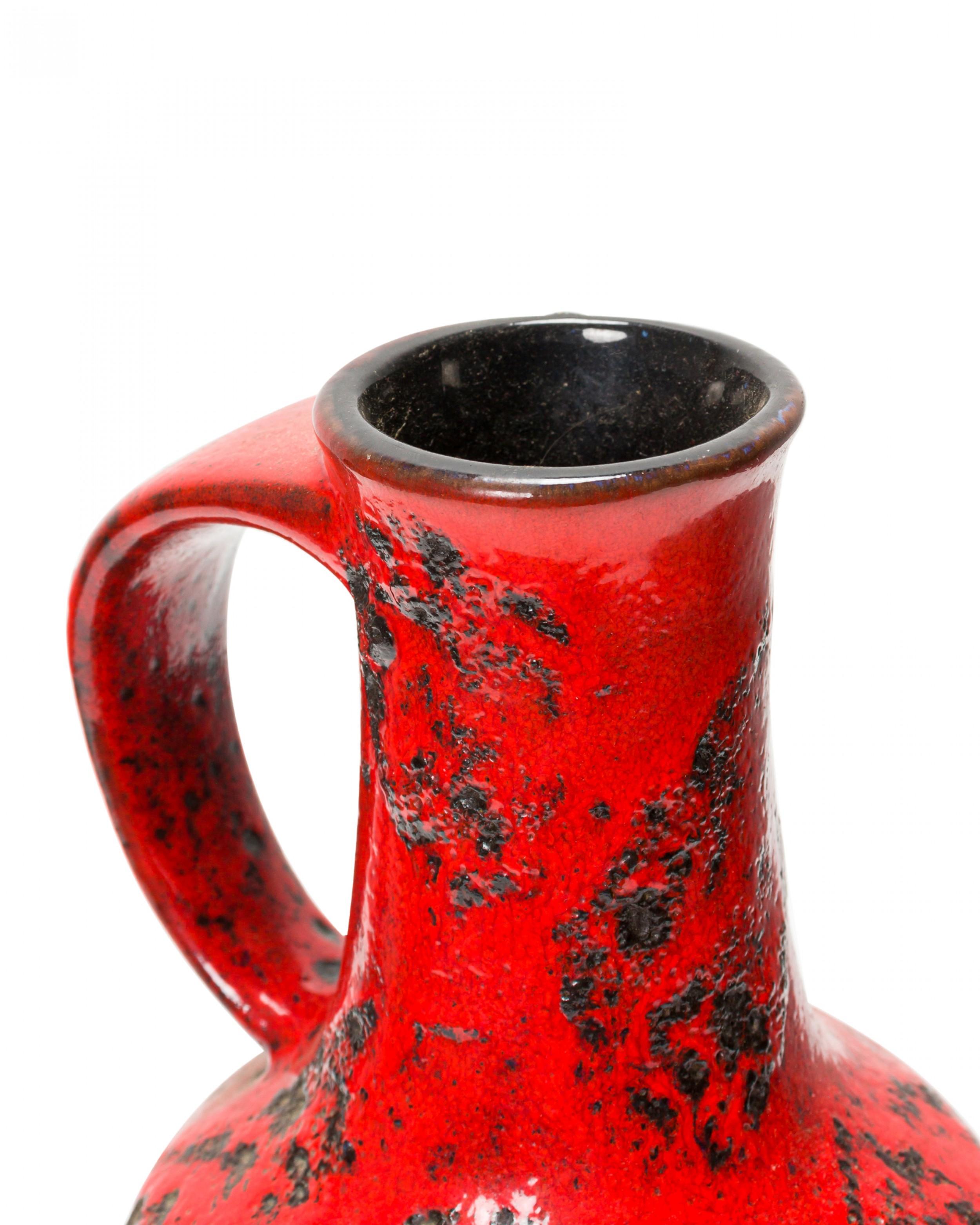 German mid-century ceramic cylindrical-form vase with a thinner neck with a rounded handle, finished in a red and black fat lava-style glaze.