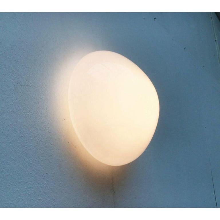 Classic ceiling or wall light after a design by Wilhelm Wagenfeld from the 1950s.

A functional, elegant and therefore timeless design. The base is designed in white. The screw glass is opal over. This piece has an attribution mark, Up to 250V
