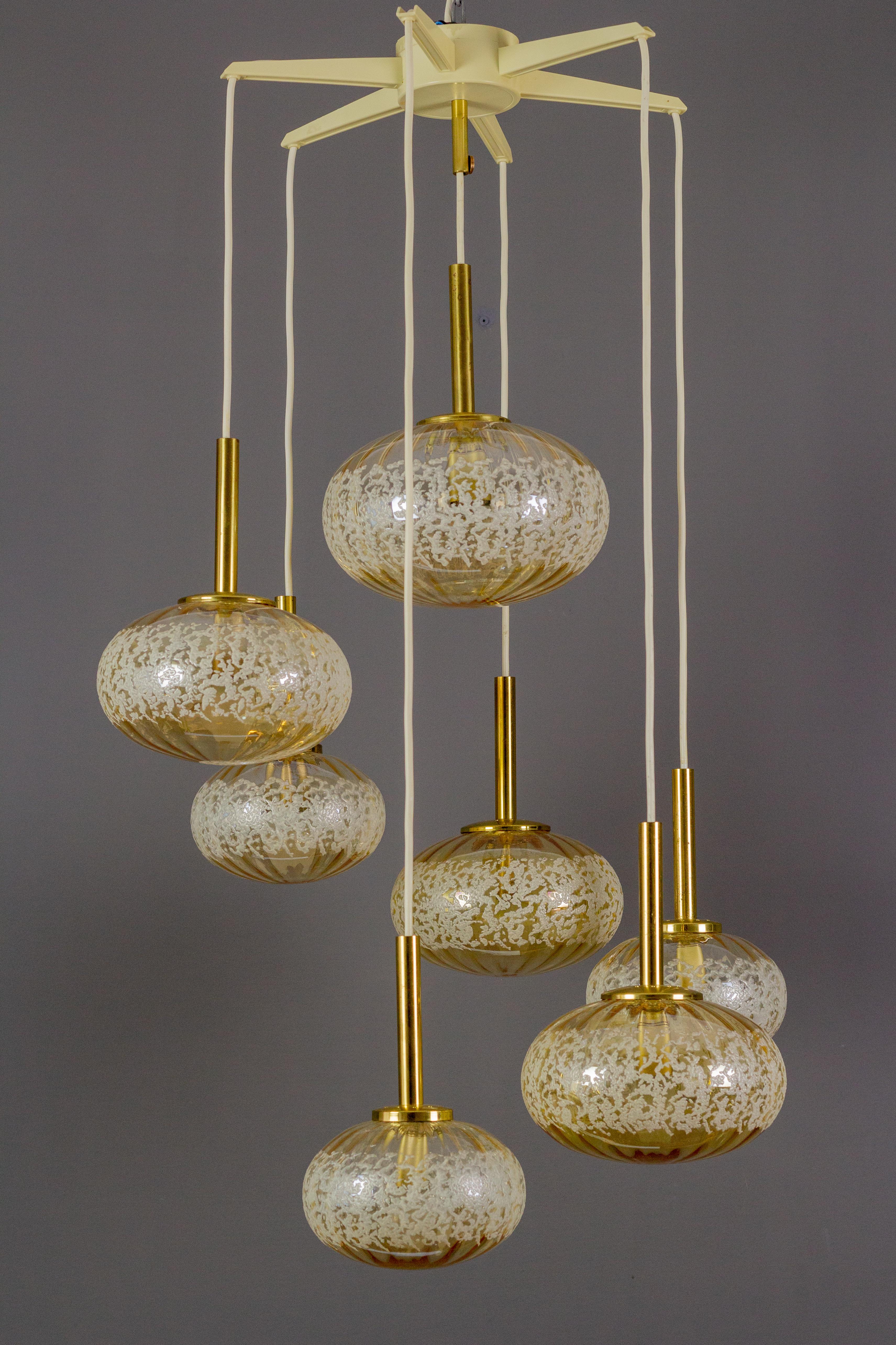 Beautiful German vintage cascading pendant light with seven very nice shaped cream color glass globes or spheres in different sizes - three smaller, three bigger, and one big glass globe. 
Six sockets for E14 size light bulbs and one socket for the