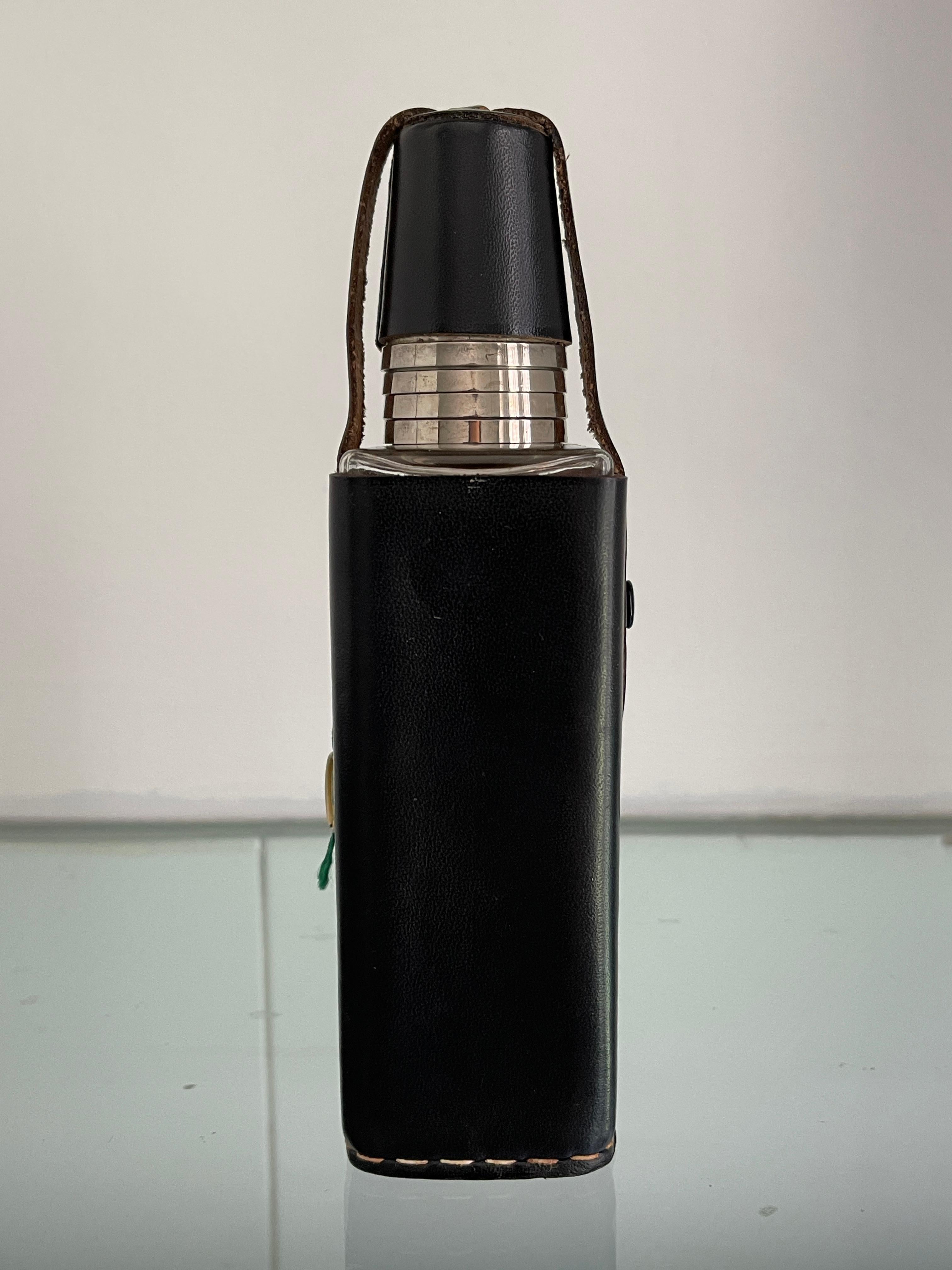 German mid-century fine hand stitched black leather covered glass flask bottle with 4 shot glasses.Top snaps off to reveal shot glasses over bottle top. Label attached, UTH Offenbacher Lederwaren Qualitatstreu.