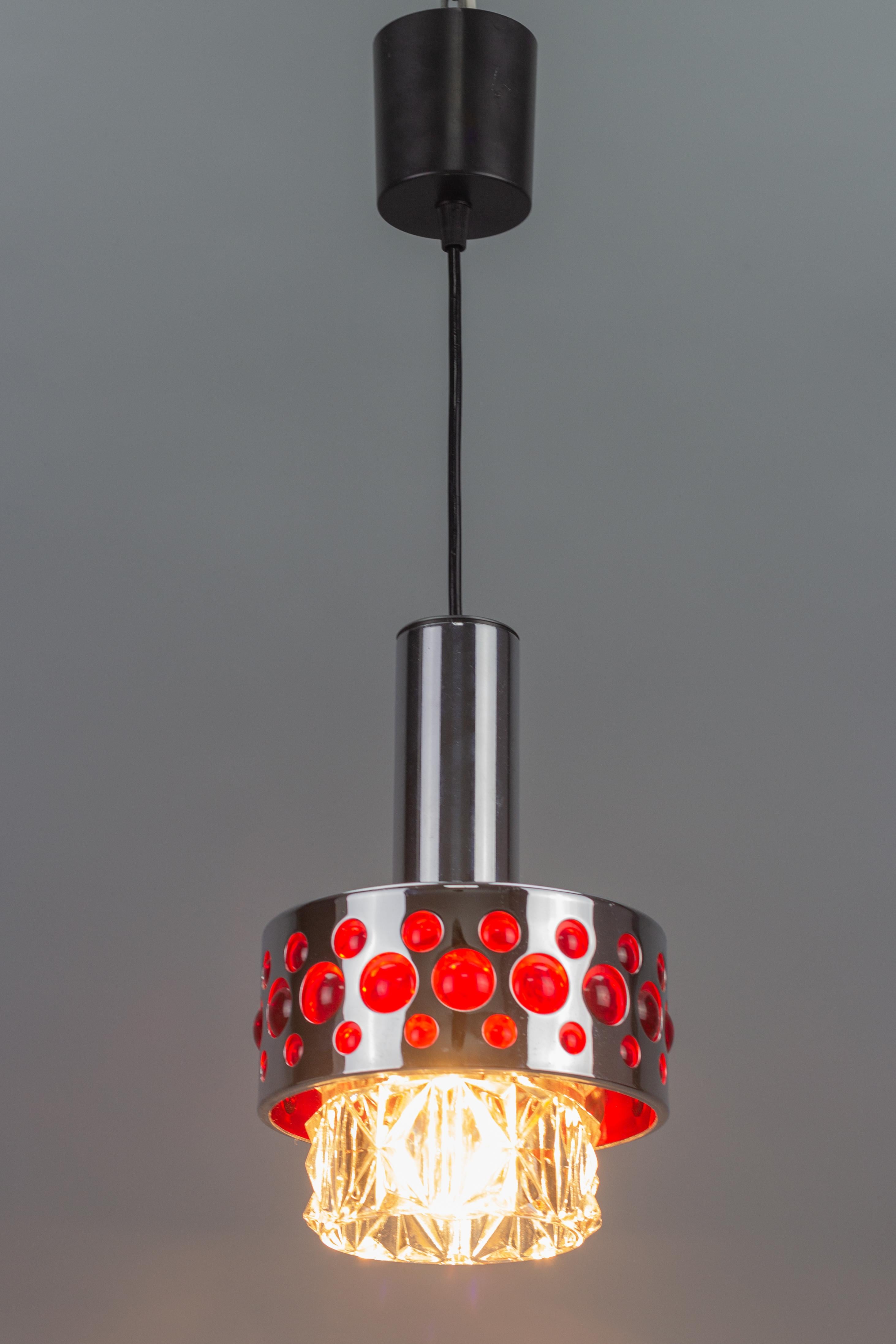 Stylish Mid-Century Modern period pendant light fixture by Richard Essig, Germany, 1970s. This adorable pendant lamp is made of chrome, clear glass, and red plastic.
One socket for E27 (E26) light bulb.
Dimensions: height: 49 cm / 19.29 in;