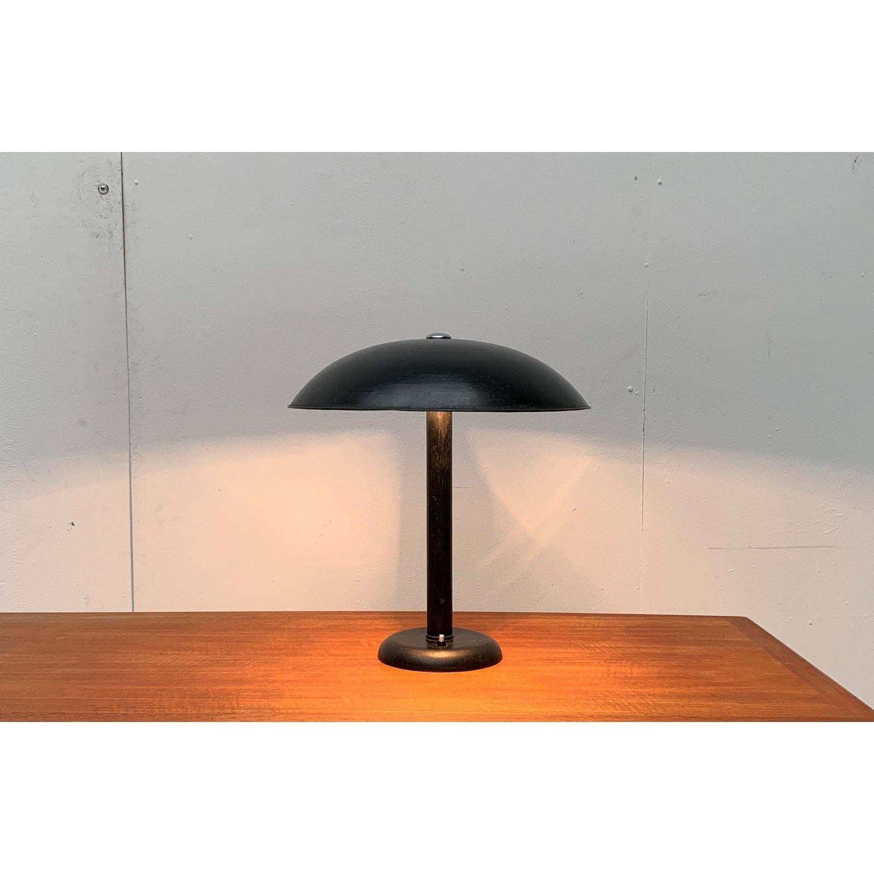 Rare lampe de table. Probablement de l'Up&Up.

Un design simple et fonctionnel. Le grand écran est monté sur un long arbre qui se termine par un lourd pied en tôle. L'écran est maintenu par une vis avec un bouton chromé, qui dépasse sur le dessus