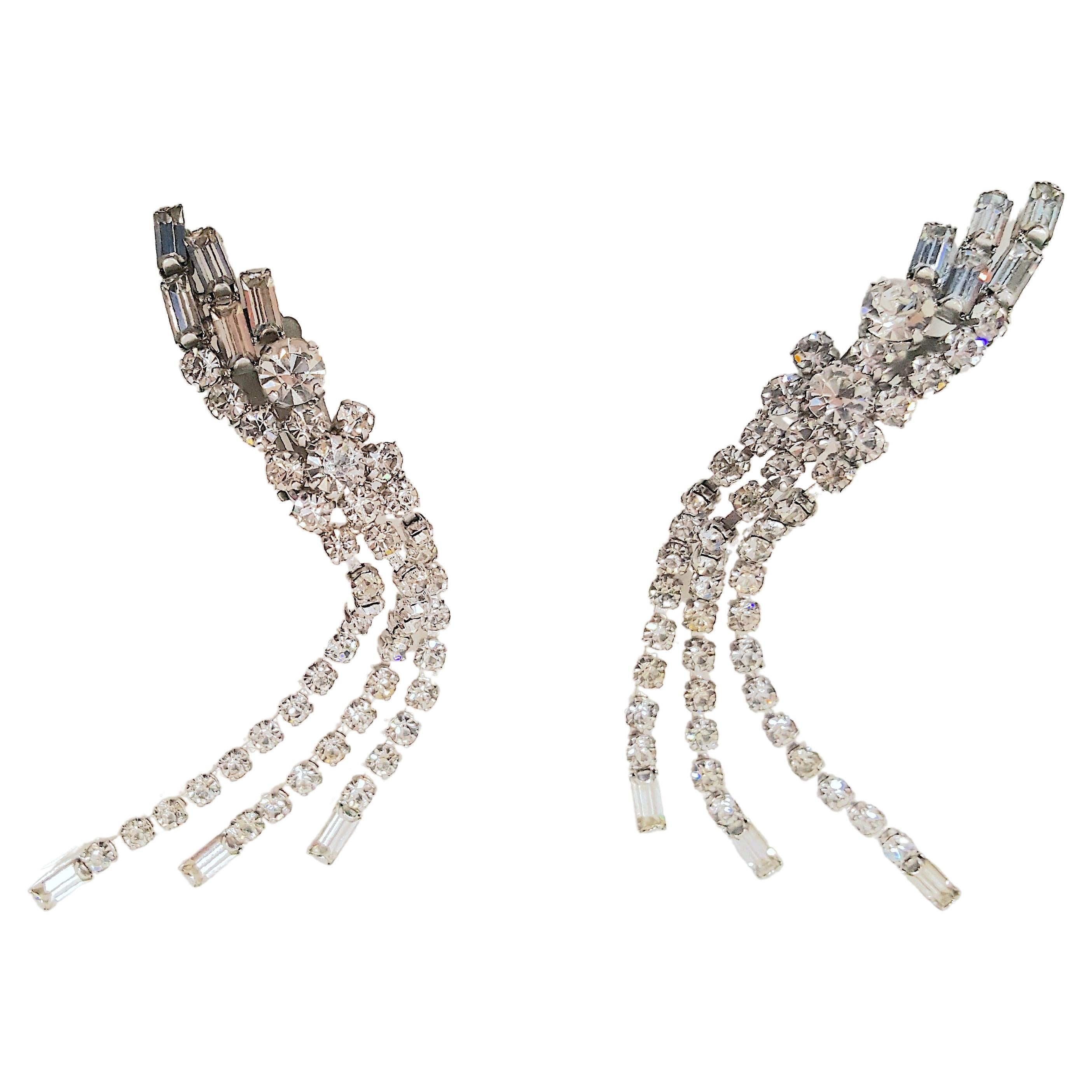 While making similar mid-century haute-couture costume jewelry for Christian Dior, designer Max Muller based near Kaufbeuren, Western Germany, created these dramatic clear-crystal silver-tone dangle earrings of graduating curvilinear sprays. When