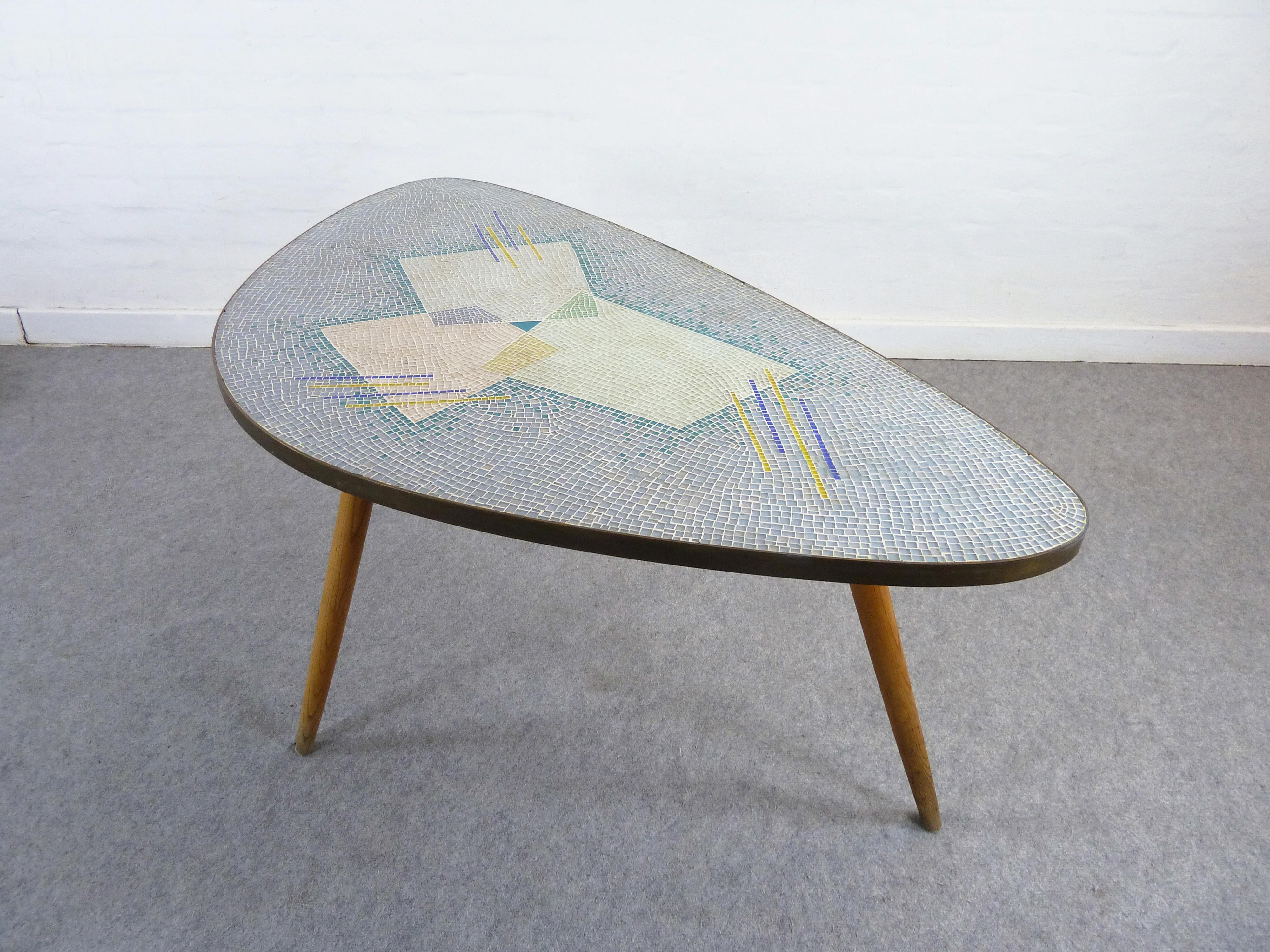 A 1950s Glas-Mosaic table by German Artist Berthold Muller-Oerlighausen (1893-1979).
Very nice pastel colors and a elegant organic form is here combined to create a nearly perfect icon of the 1950s.
The glas tiles inlay give this table a brilliant