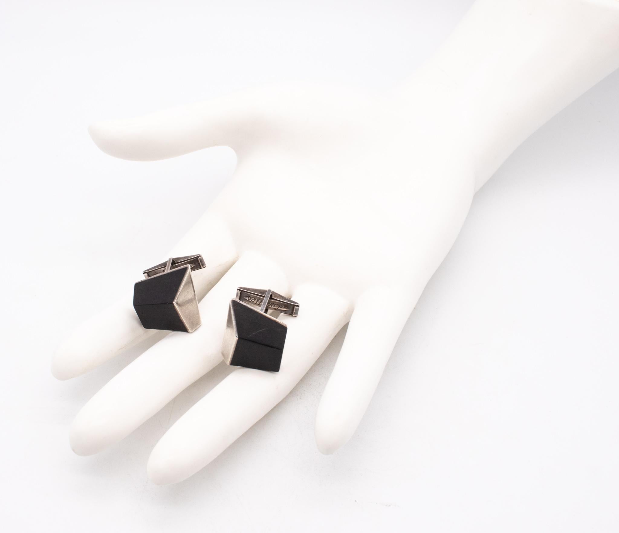 Geometric pair of ebony wood cufflinks designed by Esther Lewittes.

Very modernist geometric op-art pair of cufflinks, made in America by the jewelry artist Esther Lewittes, back in the 1950. Crafted with three dimensional patterns in solid