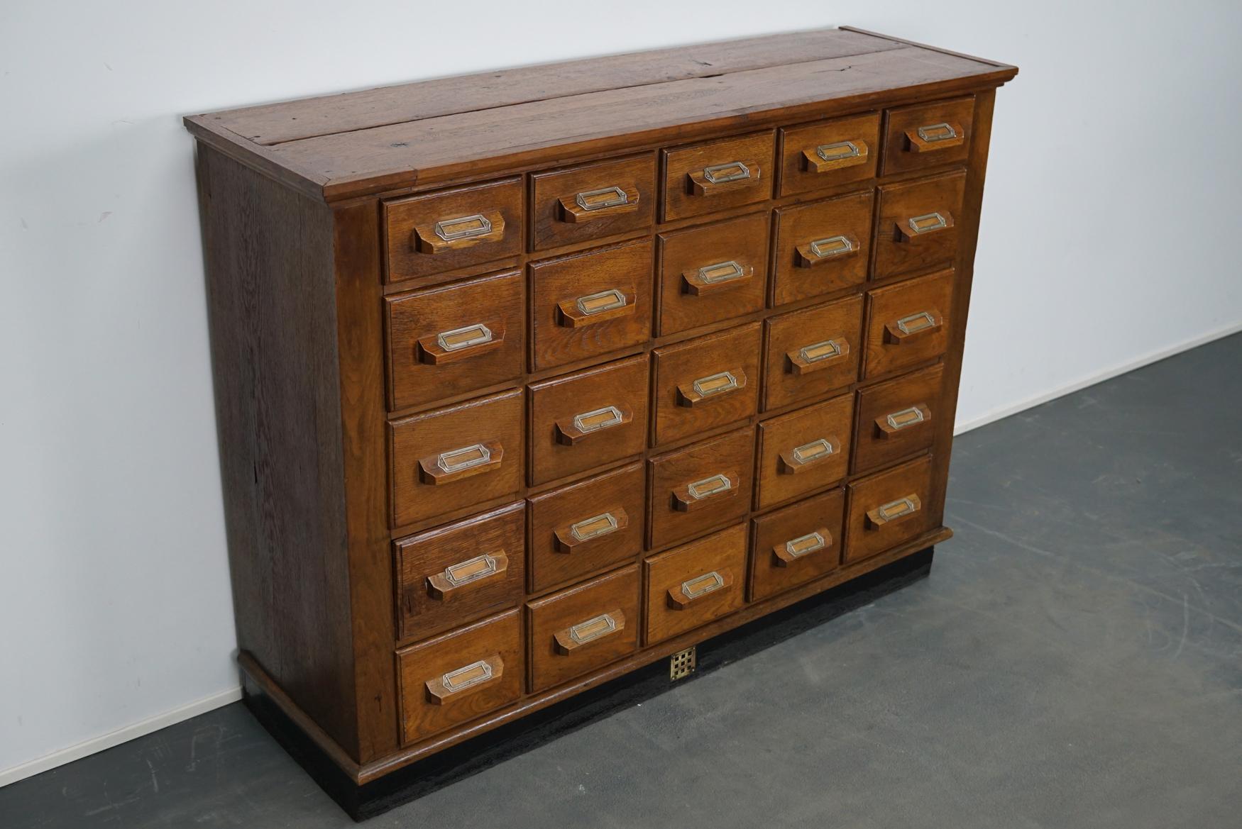 This apothecary cabinet was produced during the 1930s in Germany. This piece features 25 drawers with nice card holders and wooden pulls. The interior dimensions of the drawers are: D x W x H 33.5 x 17.5 x 13 cm and 8.5 cm for the top drawers. The