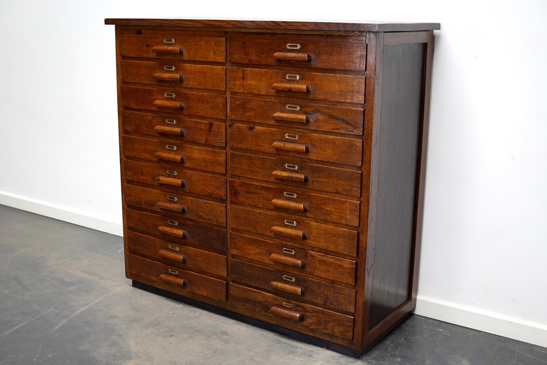 This apothecary cabinet was designed and made from oak circa 1930 in Germany. It features 20 drawers with wooden handles. The inside of the drawers measure: DWH 37 x 45 x 5.5 cm.