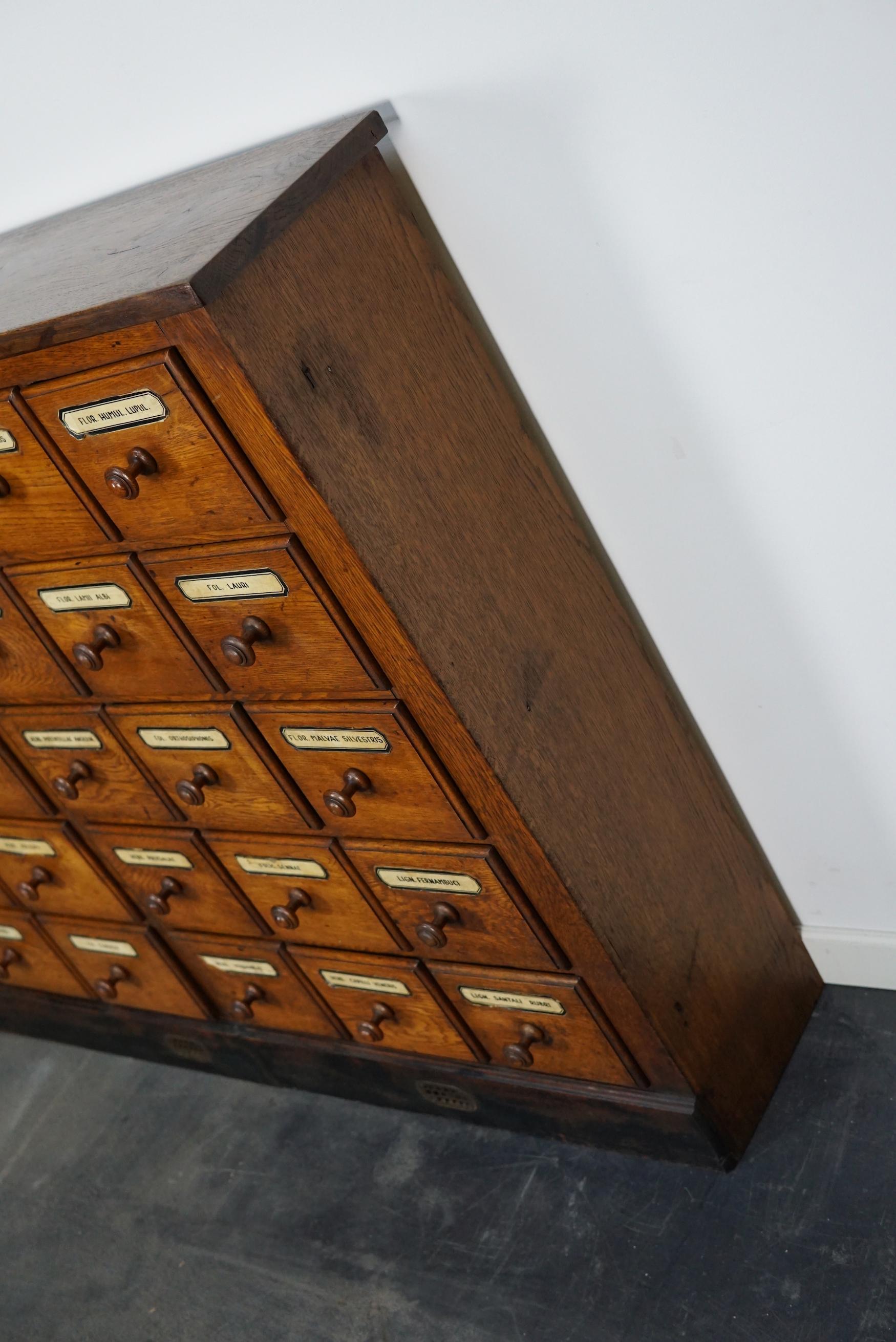 This apothecary cabinet was made circa early 20th century in Germany. The piece is made from oak and features 30 drawers with the original labels and wooden knobs. The interior dimensions of the drawers are: DWH 18 x 17 x 11.5 cm and 18 x 14 x 11.5