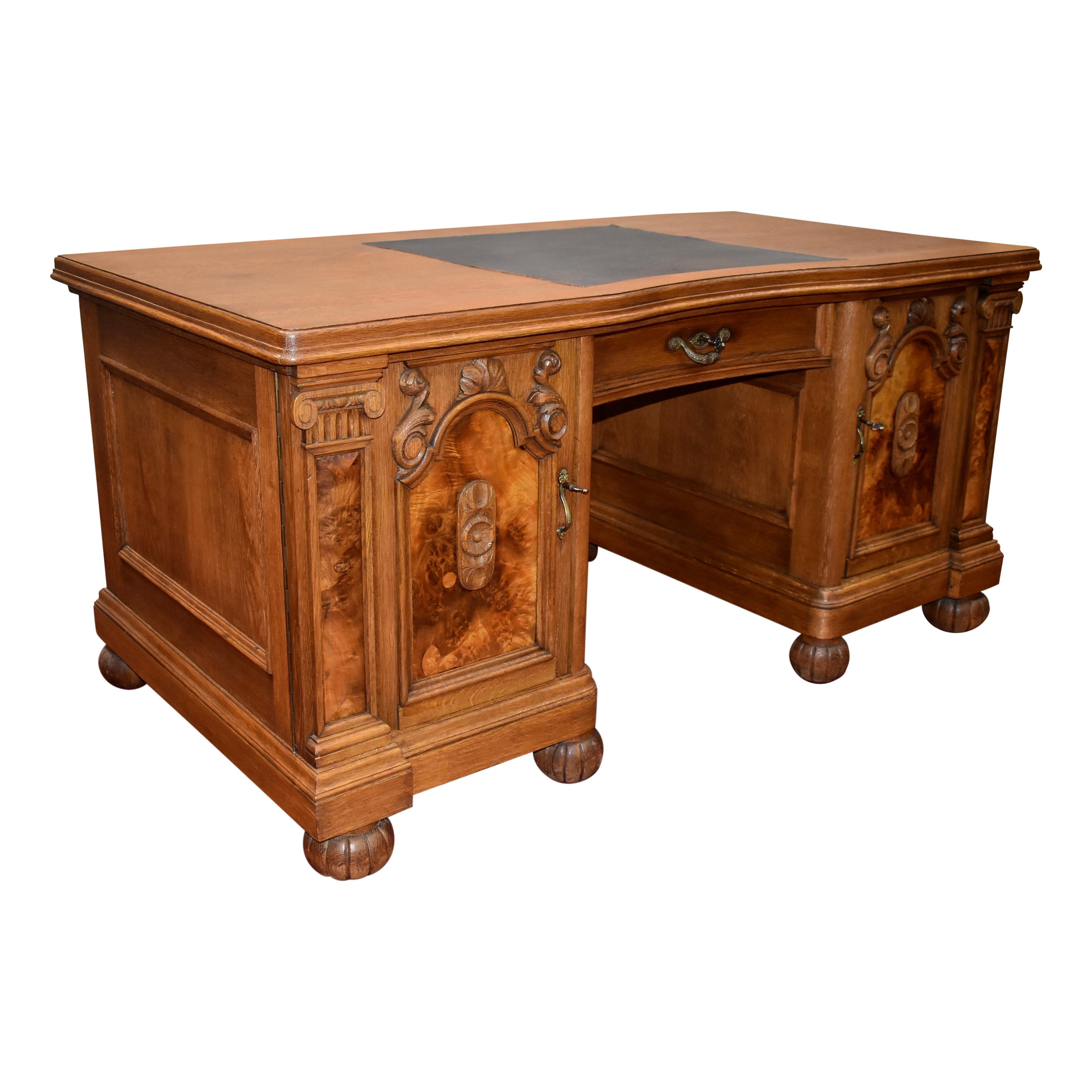 Beautiful from every angle, this German desk showcases a rectangular top over a single drawer flanked by two pedestals. The top features a beveled edge and leather writing surface at the center. The pedestals feature arched doors with recessed