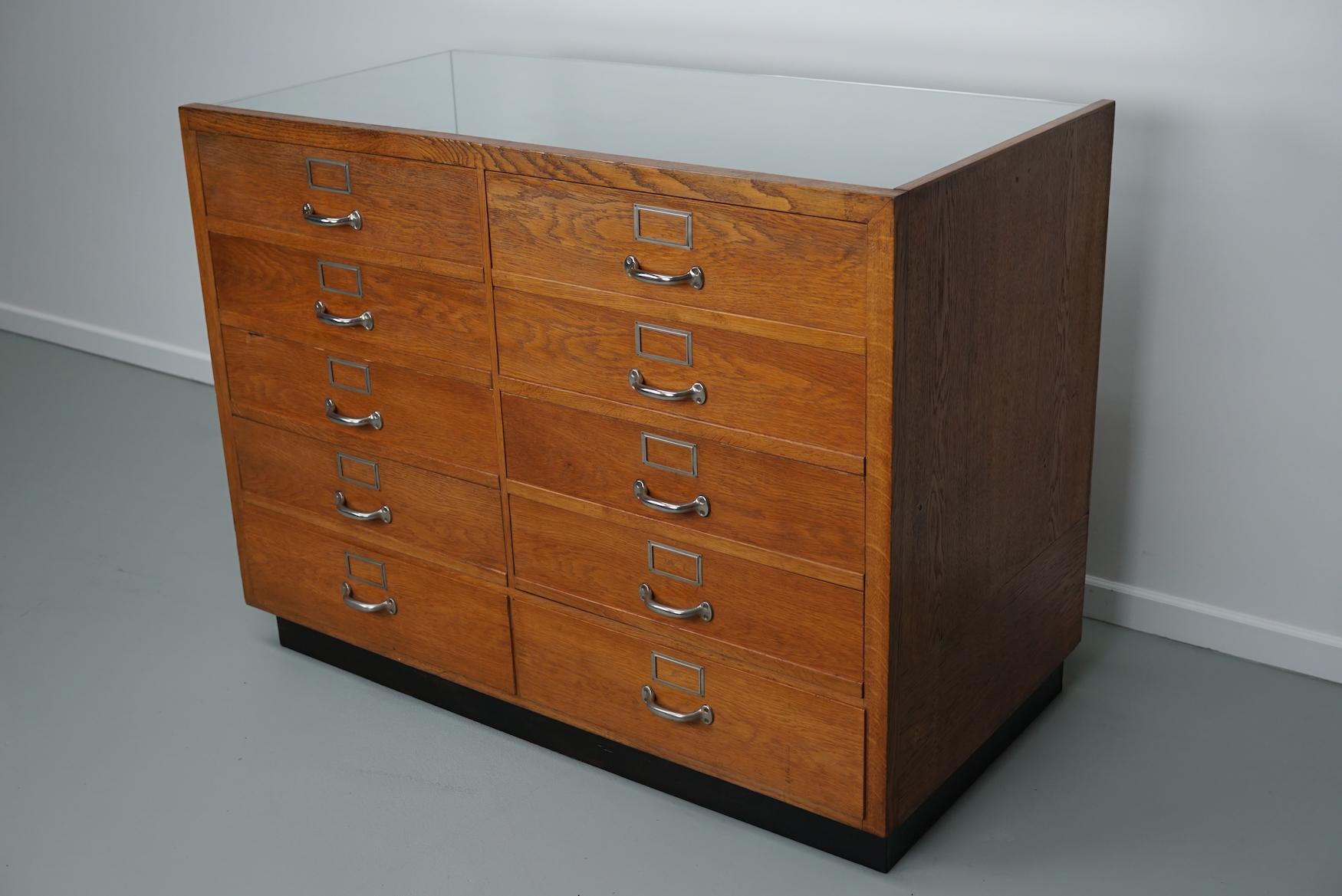 This shop counter was made and manufactured during the 1950s in Germany. It features an oak frame with oak drawers with chrome metal handles and a glass casing. It remains in a good vintage condition with some marks consistent with age and use.