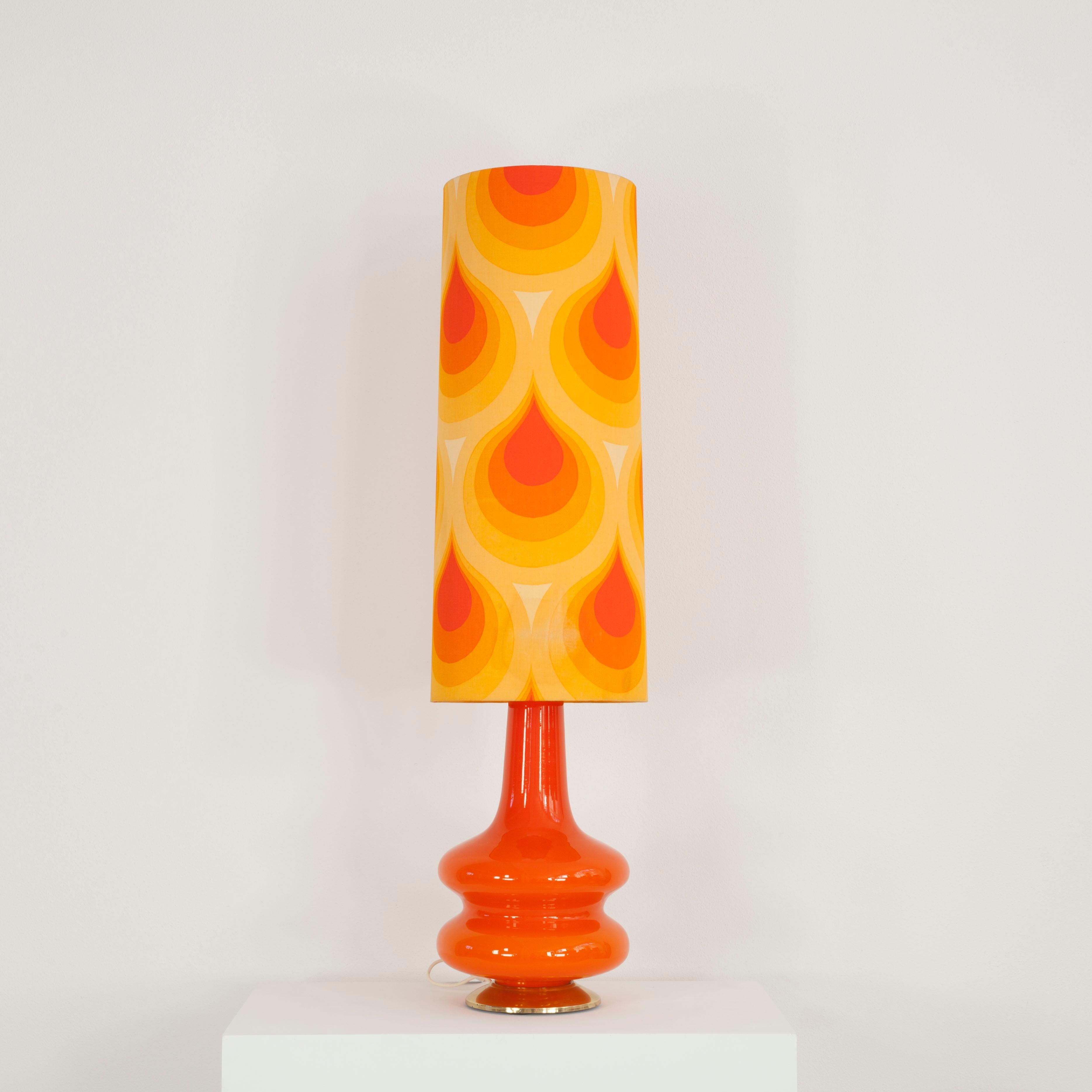 This floor lamp was made in the 70s. It consists of an illuminated glass base and a fabric shade with a typical 70s motif. 
The lamp can be switched separately in 3 ways - base only, shade only or both together.
Manufacturer: Doria, Germany.