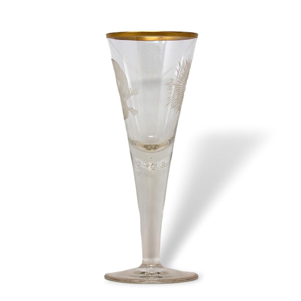 Unusual 1920's German oversized glass flute. The flute with circular base and tapered body with gilt rim opening and stylised bubble decoration within the stem. To each side etched decoration with a Memento mori to one side and an insignia reading