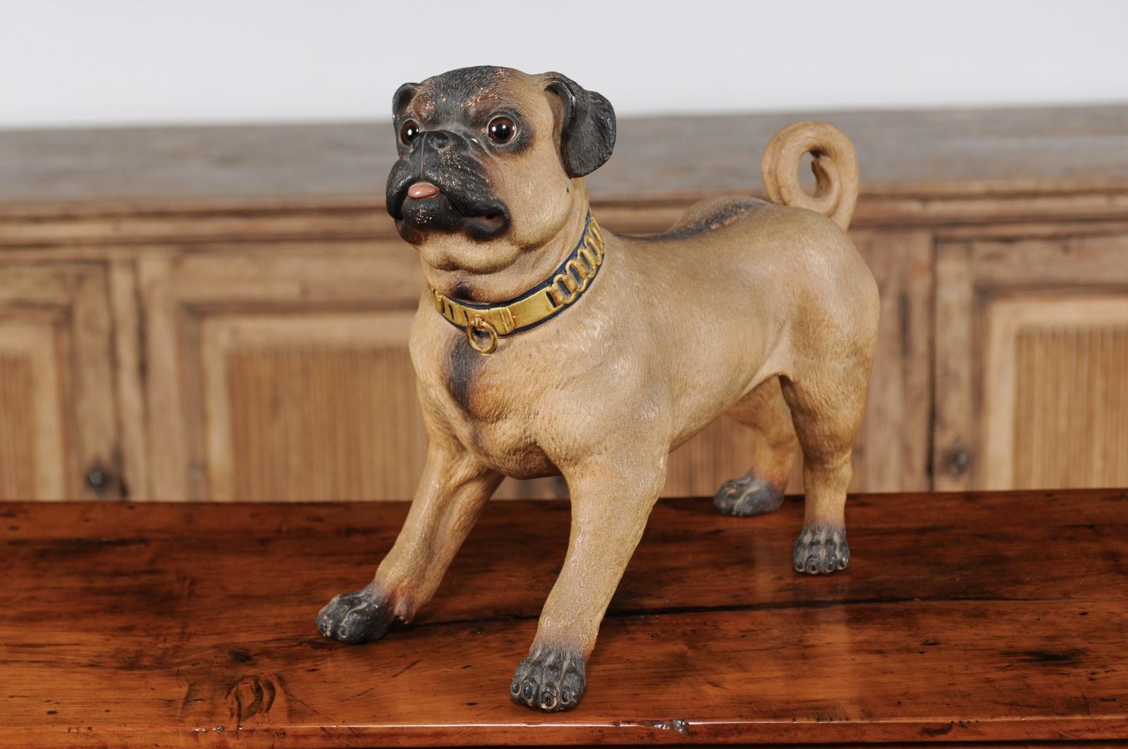 A German painted terracotta pug sculpture from the early 20th century, with gilded collar and playful attitude. This adorable German animal sculpture melts our hearts with its lively depiction of a pug, standing on his four paws. His attention is