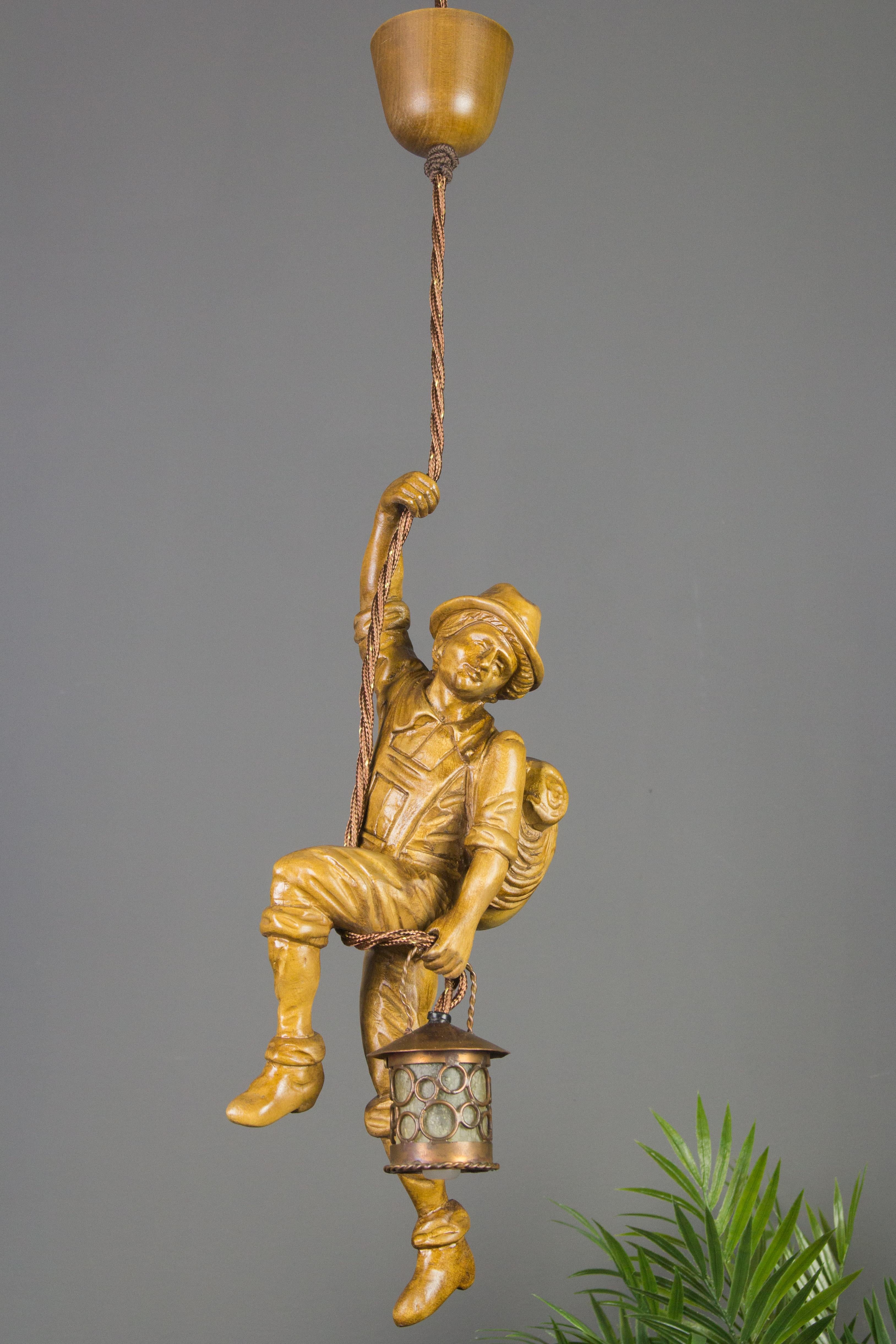 Wonderful German Black Forest figural pendant lamp features a hand-carved figure of a mountain climber. The detailed carved wooden mountaineer with a backpack is holding onto a rope and holding a copper lantern in one hand.
The height of the pendant