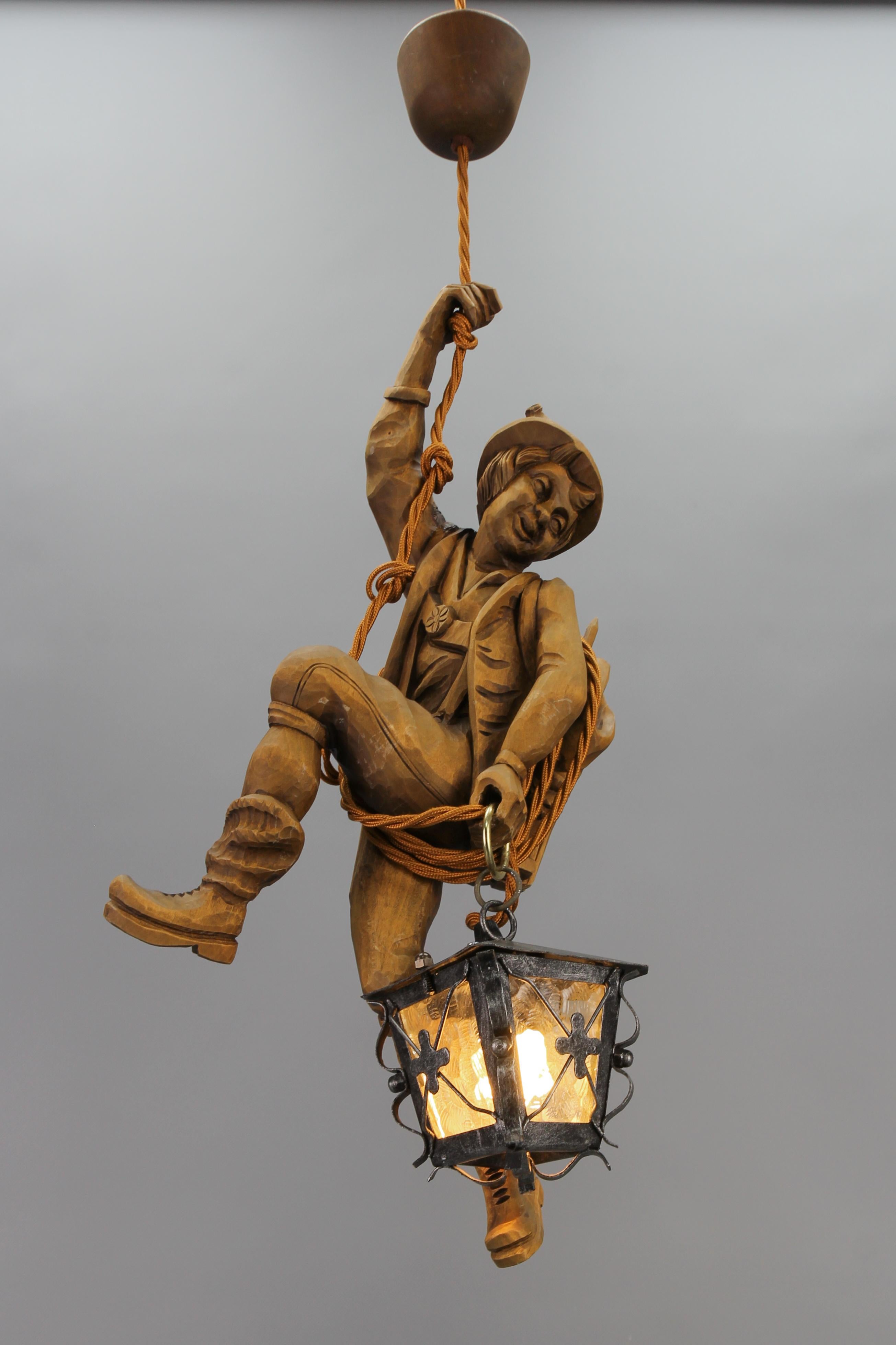 German Pendant Light with Carved Wooden Figure Mountain Climber and Lantern
This wonderful German figural pendant lamp features a hand-carved linden wood figure of a smiling mountain climber. The detailed wooden mountaineer is holding onto a rope