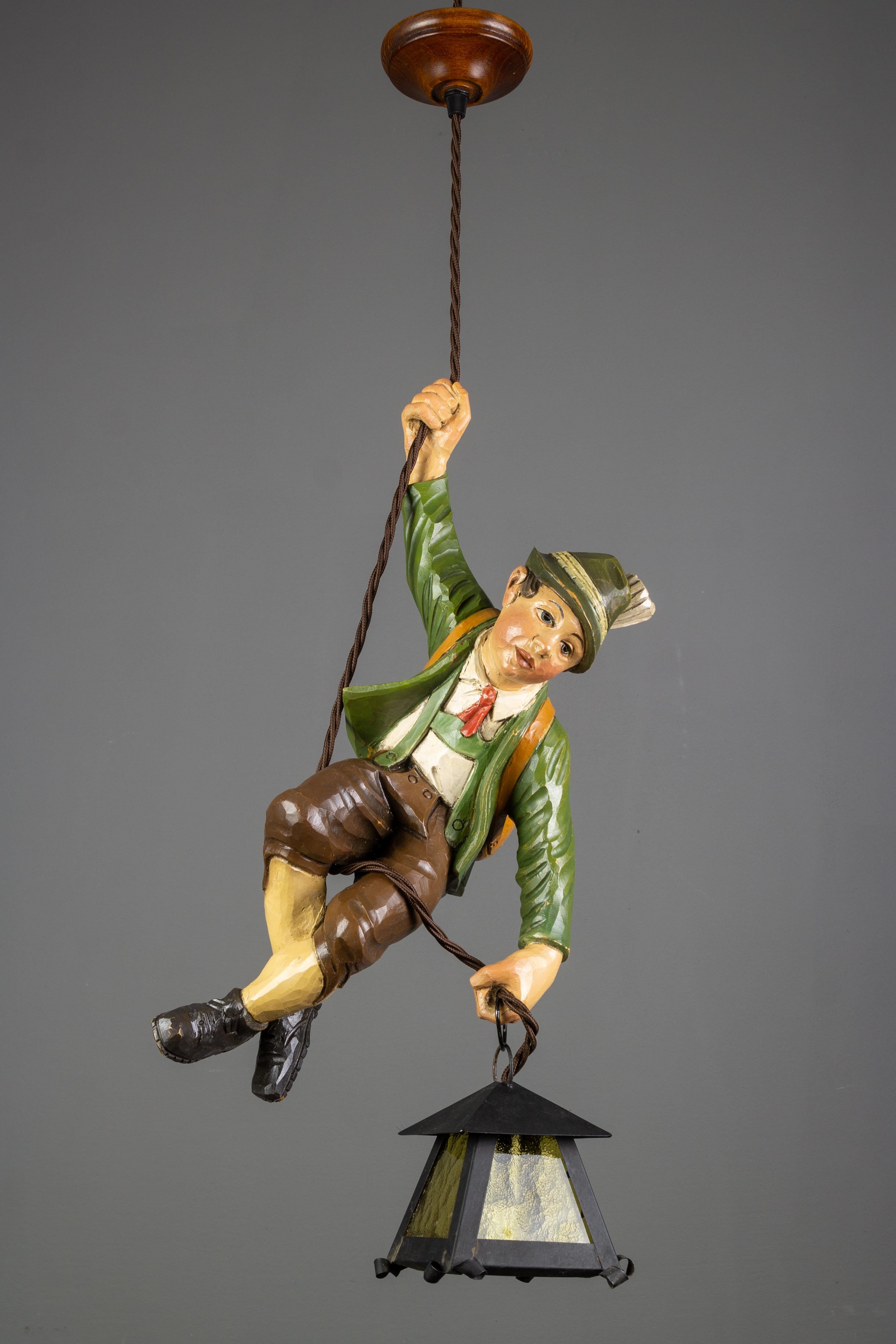 Wonderful German pendant lamp or Lüstermännchen features a hand carved figure of a mountain climber in beautifully hand painted Bavarian traditional clothing in brown, green, white, and red colors. The detailed carved wooden mountaineer wears a hat,