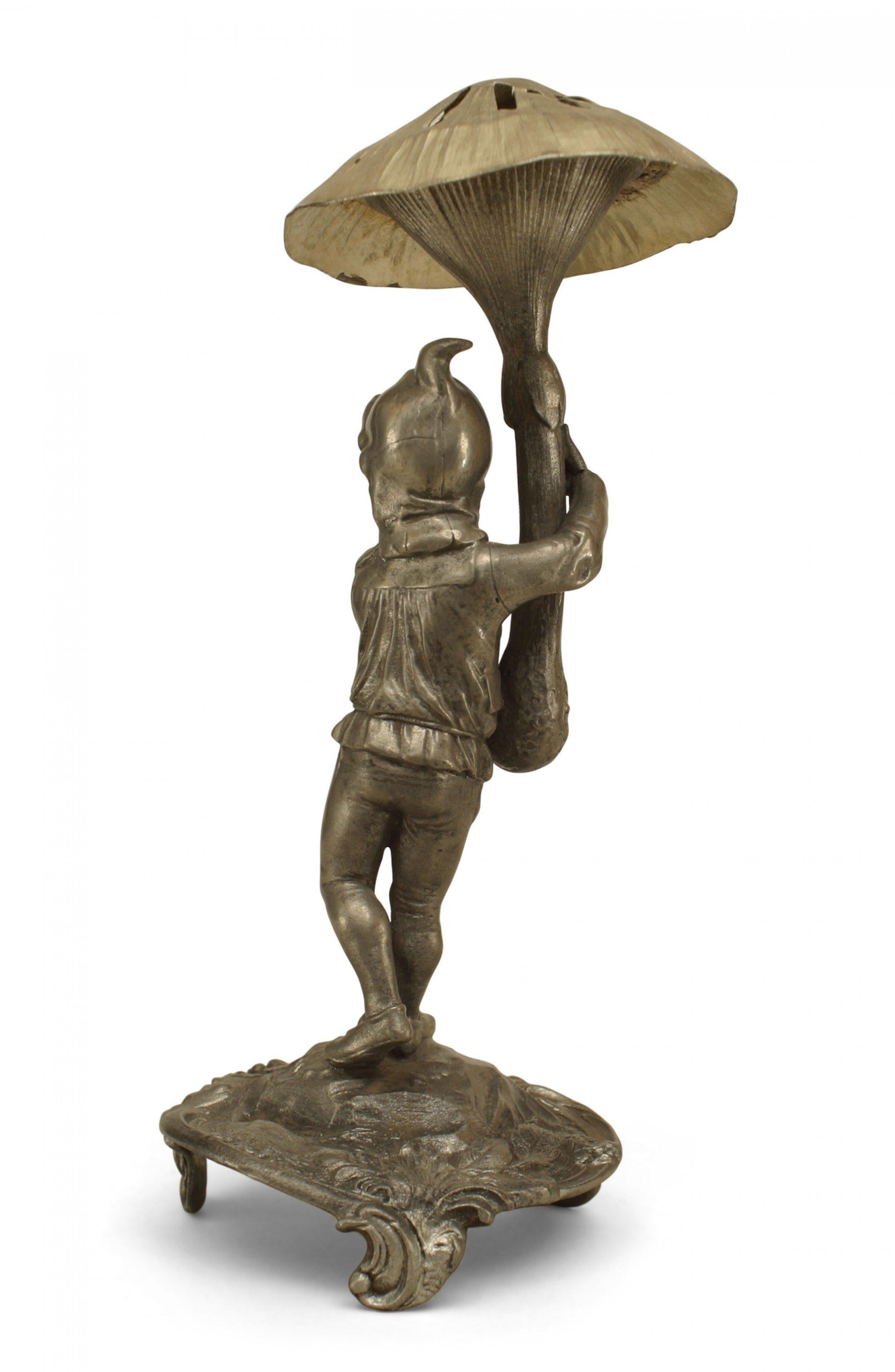 Continental German (19/20th cent) pewter small figure of a gnome holding a mushroom with a perferated top (toothpick holder) and standing on a stylized round base (WMF).
     