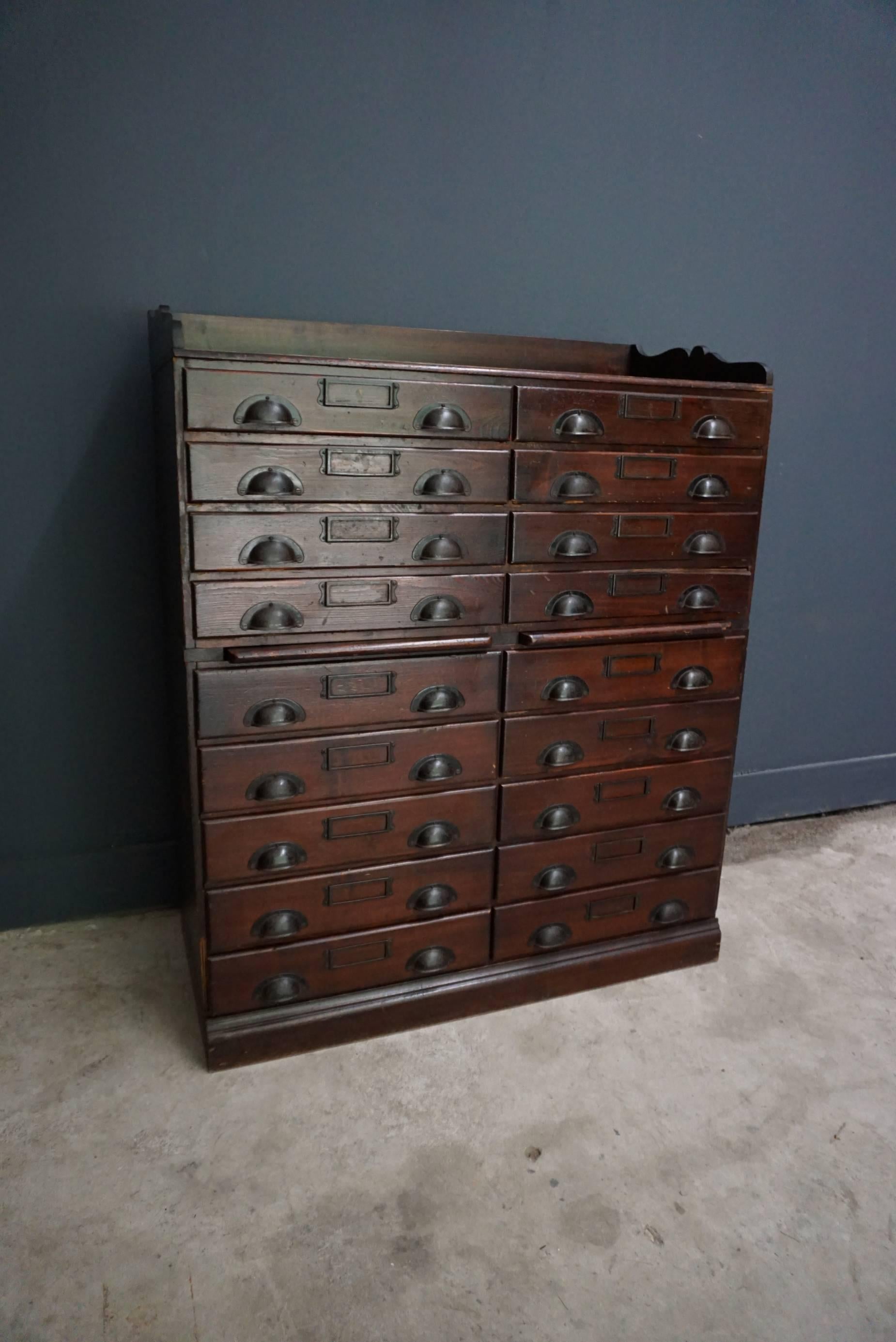 This pine apothecary cabinet was designed and made circa 1950 in Germany. It features 18 drawers with metal hardware and remains in a very good vintage condition. The cabinet is assembled from stackable units and was used in a jewelers store to