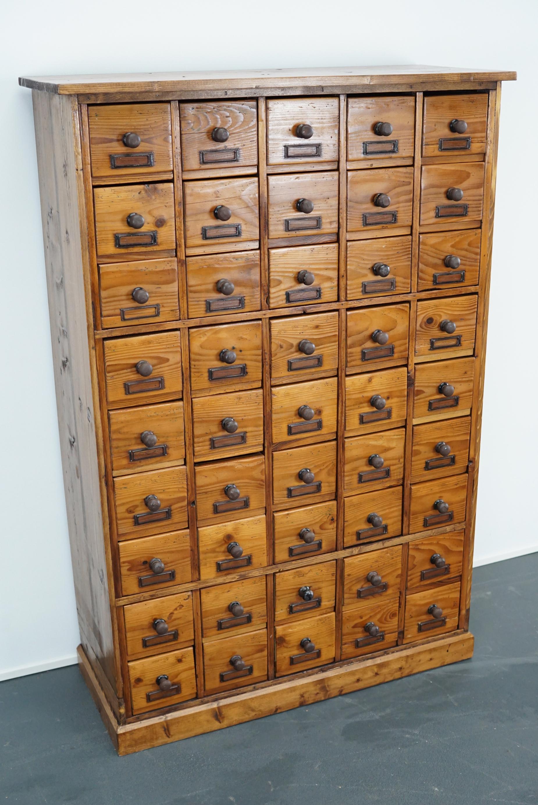 This apothecary cabinet of drawers was designed, circa 1930s in Germany. The piece is made from pine and features 45 drawers with metal hardware. The interior dimensions of the drawers are: W 12.5 x D 28 x H 9.5 cm.