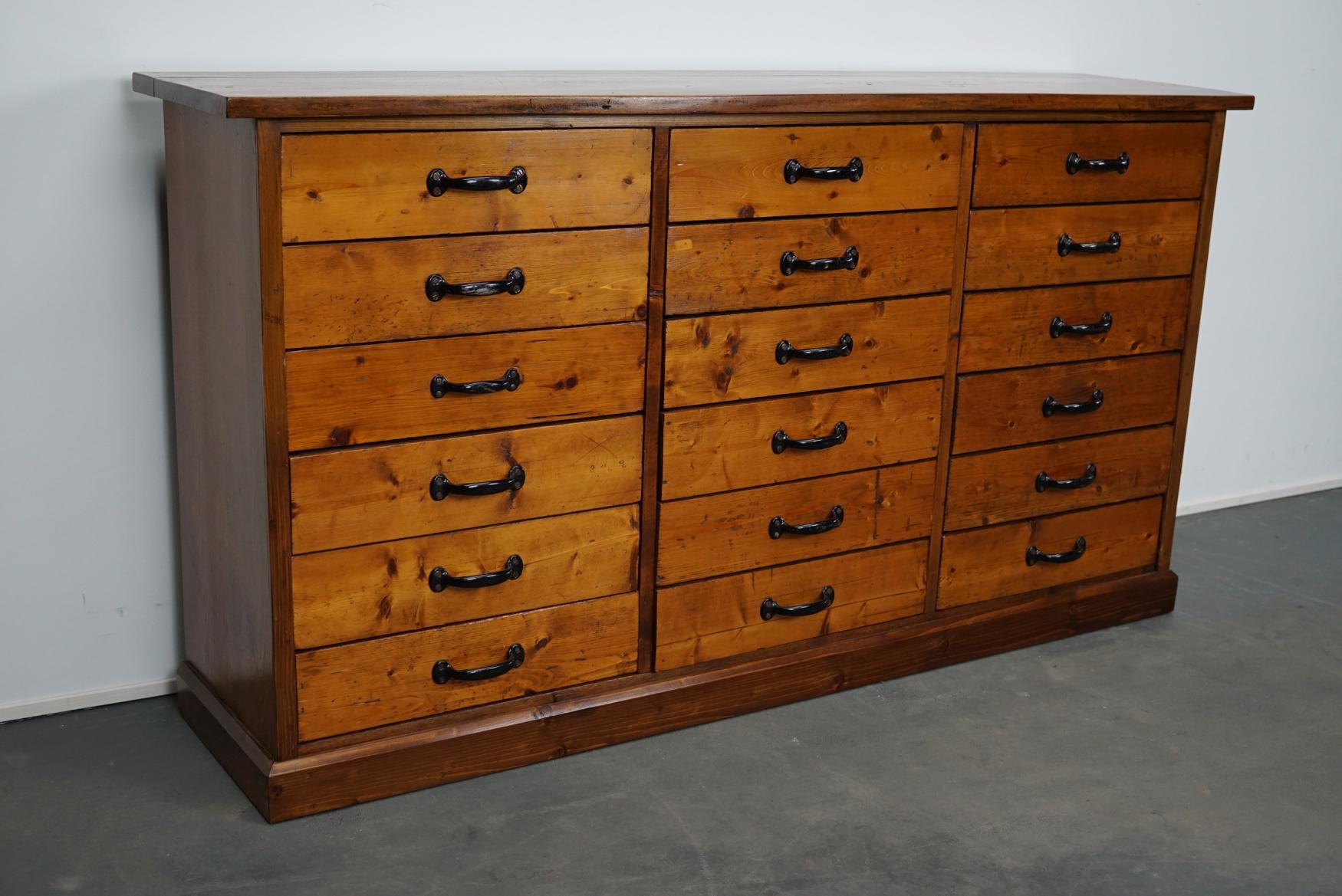 This apothecary cabinet of drawers was designed, circa 1950s in Germany. The piece is made from pine and features 18 drawers with metal hardware. The interior dimensions of the drawers are: D 29.5 x W 44 x H 10 cm.