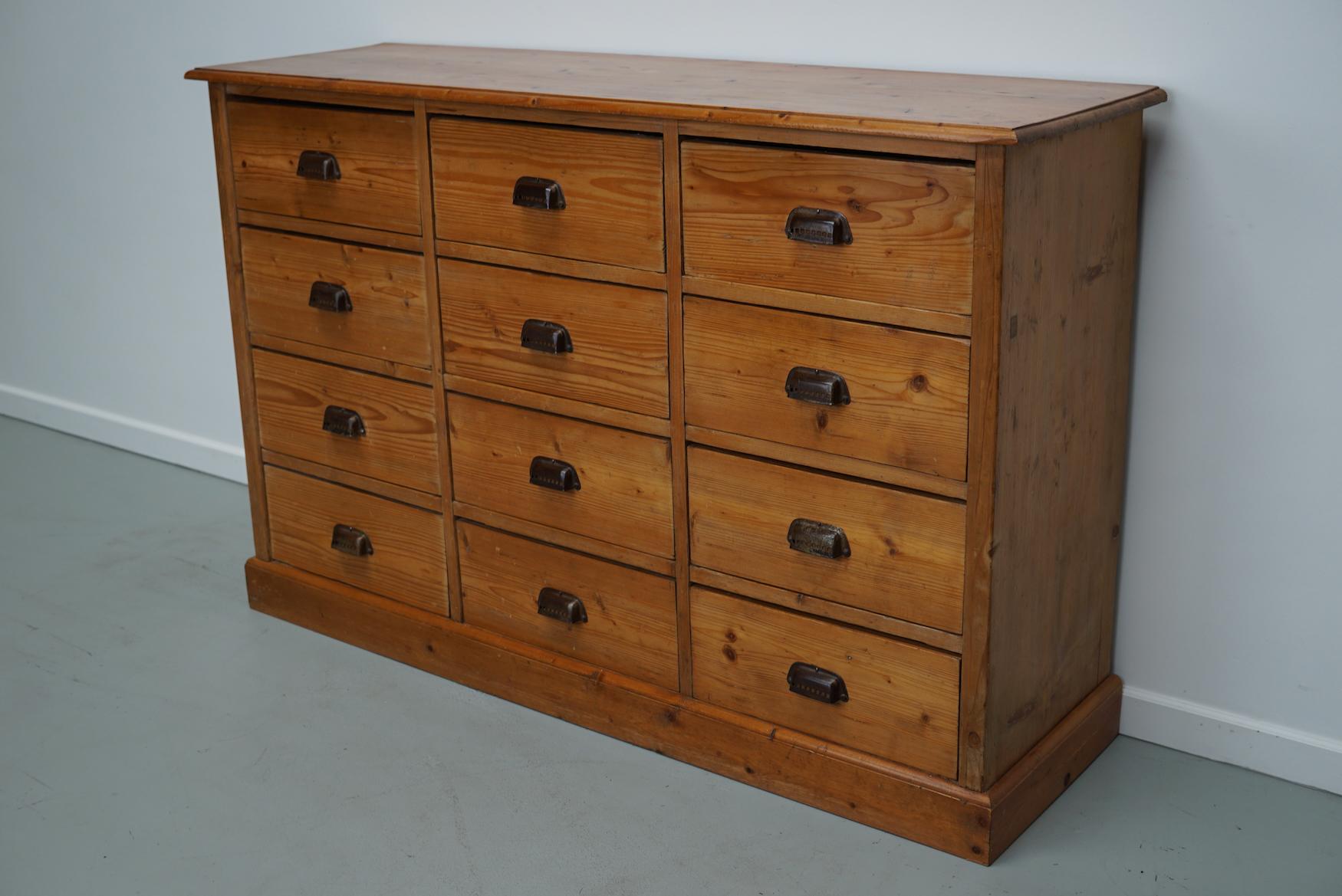 This apothecary bank of drawers was designed and made circa 1930. It was made from pine and it features 12 drawers with metal handles. The interior dimensions of the drawers are: DWH 33 x 37 x 15 cm.