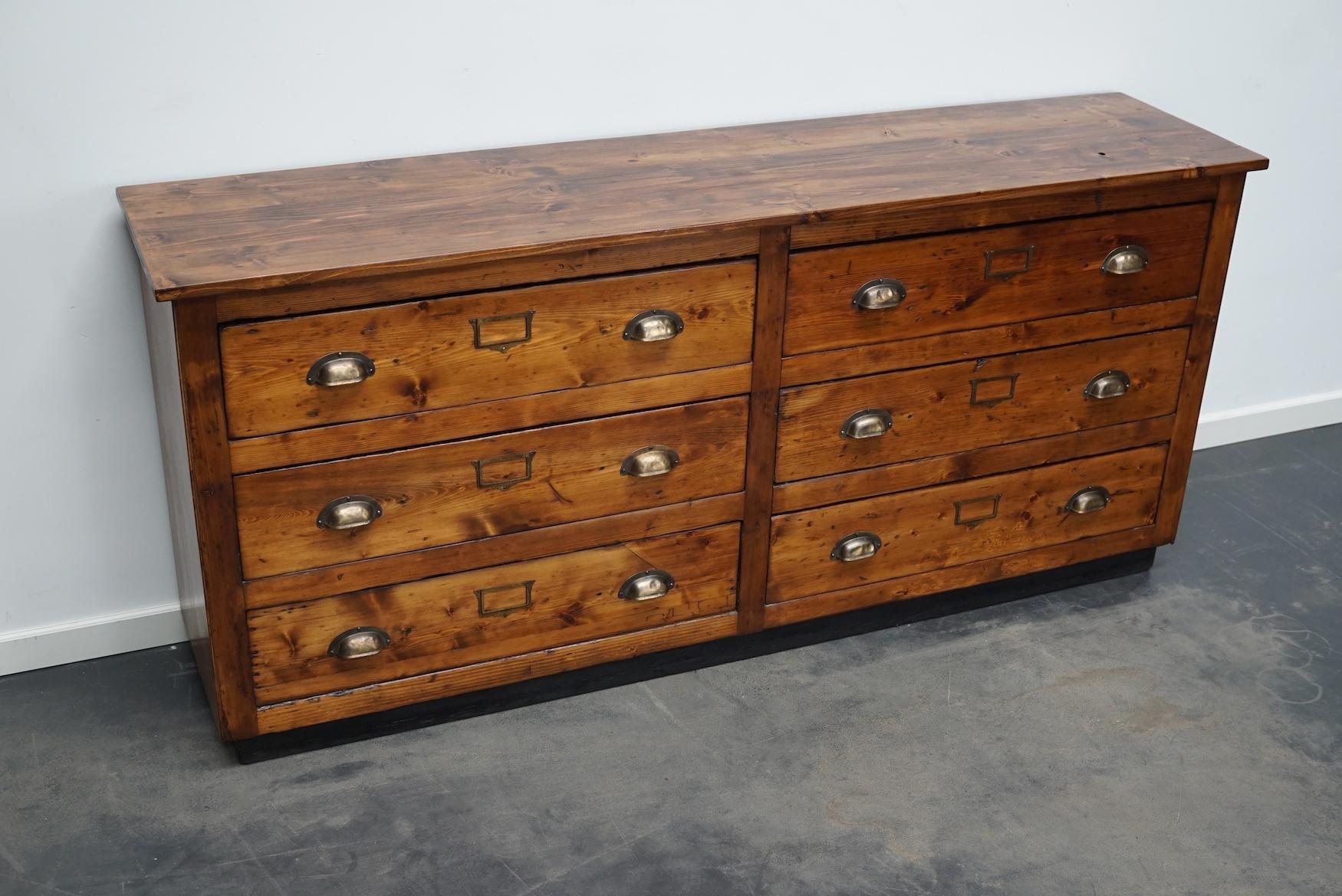 This apothecary cabinet was made from pine circa 1940 / 1950s in Germany. It features 6 decent sized drawers with nice brass handles and name card holders. The interior dimensions of the drawers are: DWH 31 x 71 x 13 cm.