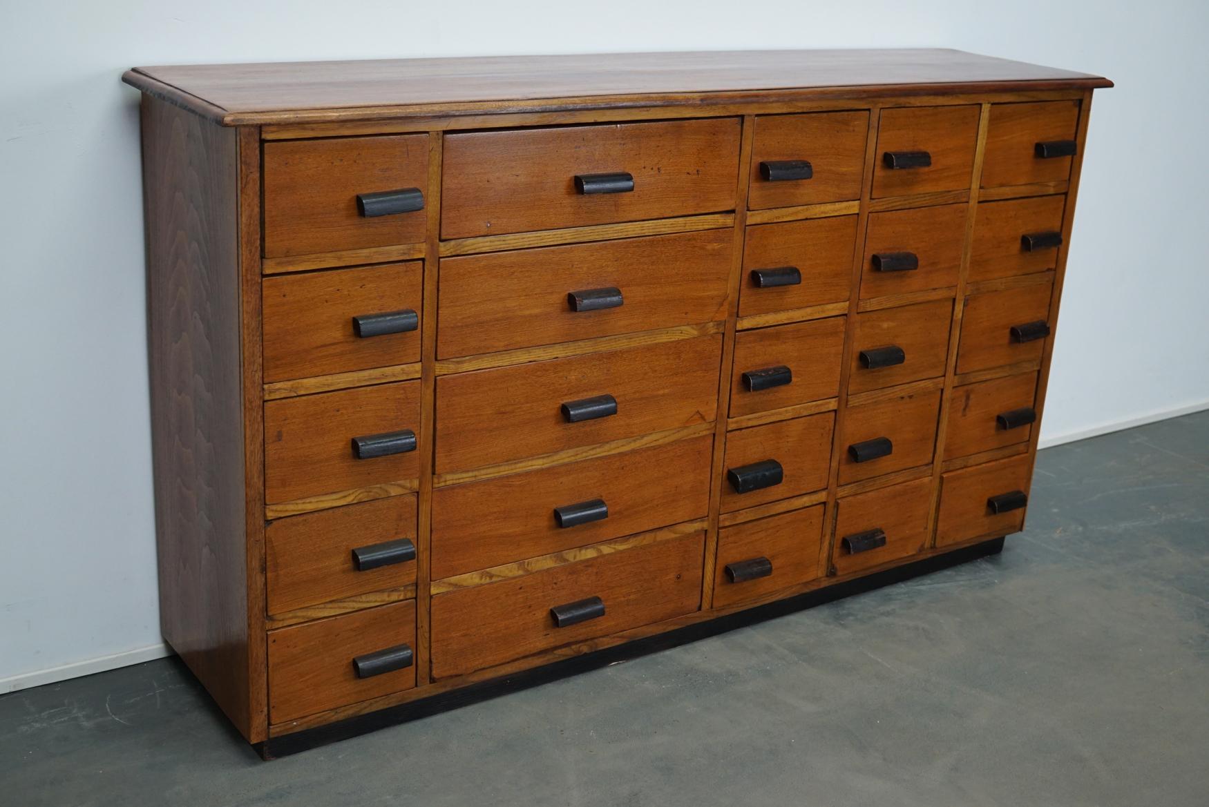 This apothecary cabinet was made in Germany, circa 1940s. It features 25 drawers in two sizes with nice black wooden handles. It is made oak and pine and it retained a nice patina from years of use. The interior dimensions of the drawers are: Large