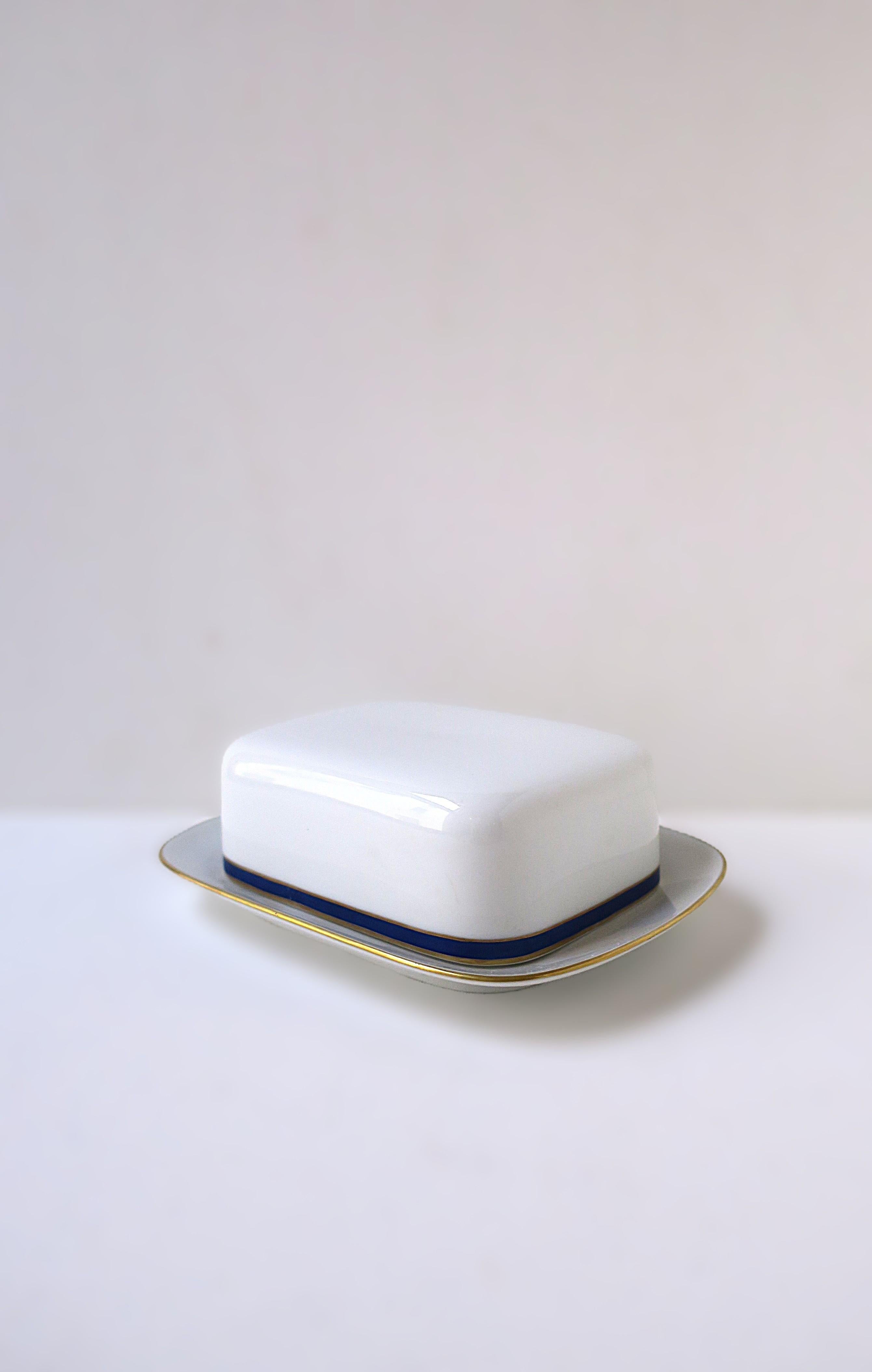 A German porcelain butter dish with lid, by Thomas Porcelain, circa mid-20th century, Germany. Piece is white porcelain with gold and cobalt blue edge around base of lid, gold detail around edge of plate. Fits European rectangular butter or American