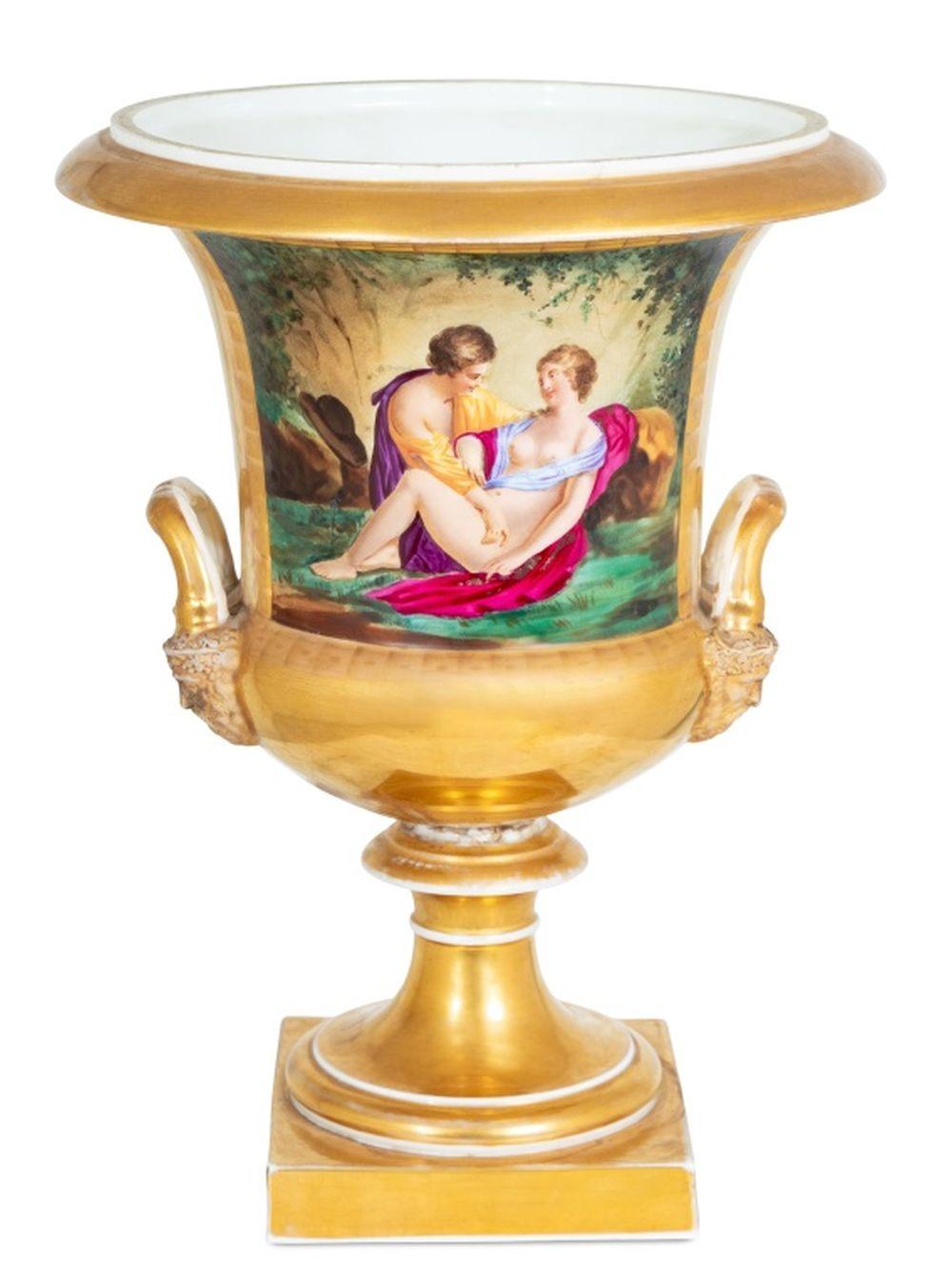 German Porcelain Two-Handled Campagna Urn Vase, late 19th century, the body painted with a panel of Apollo and Aphrodite and an interior scene of two women playing cards with a cat, richly gilded, mask head handles on a square plinth. 15.5