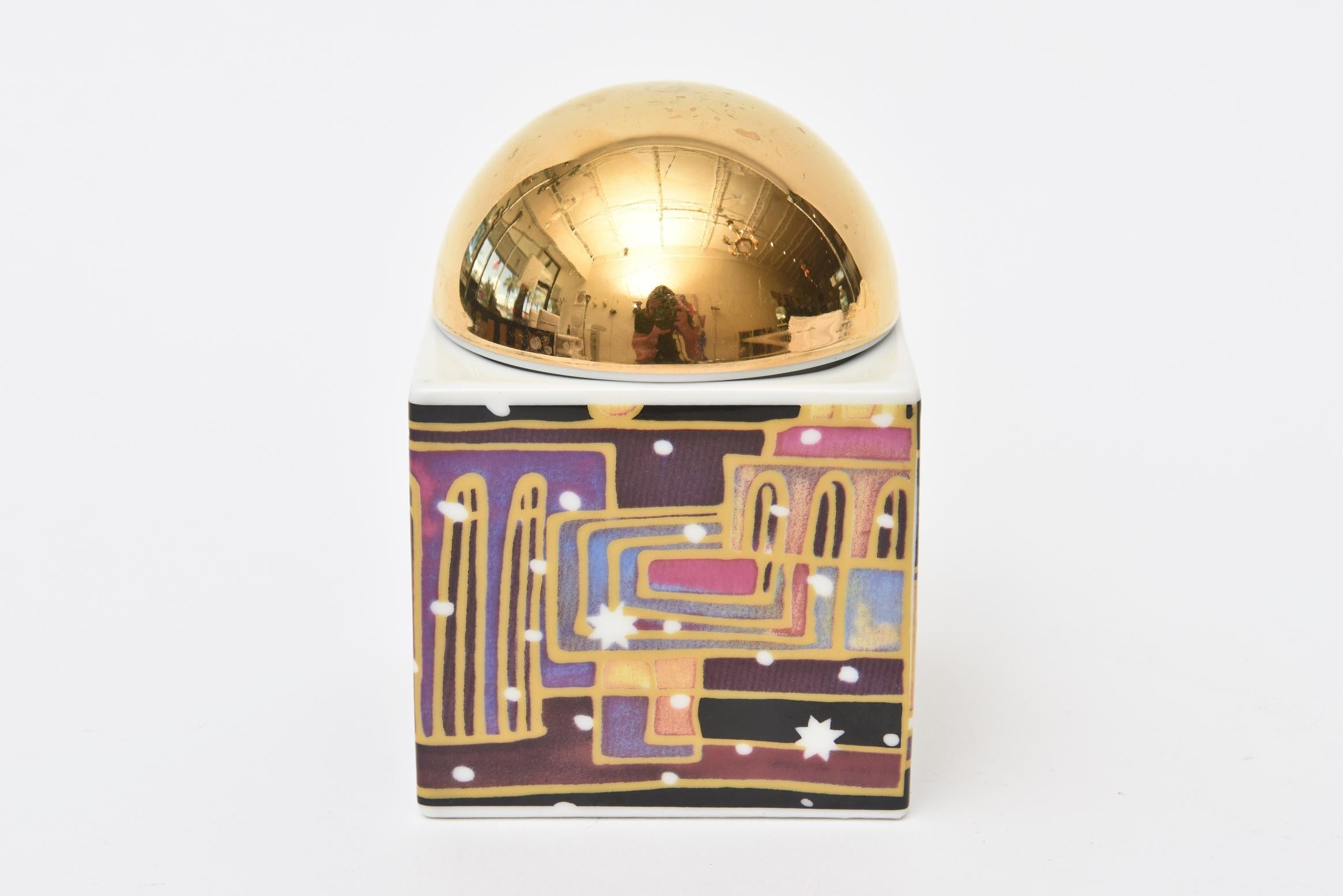 This lovely German small porcelain modern hand-painted and gold-plated 2 part dome box has architectural renderings in the style of the artist: Hundertwasser. The sides are all different of architectural imagery. The play of colors are gold, purple,