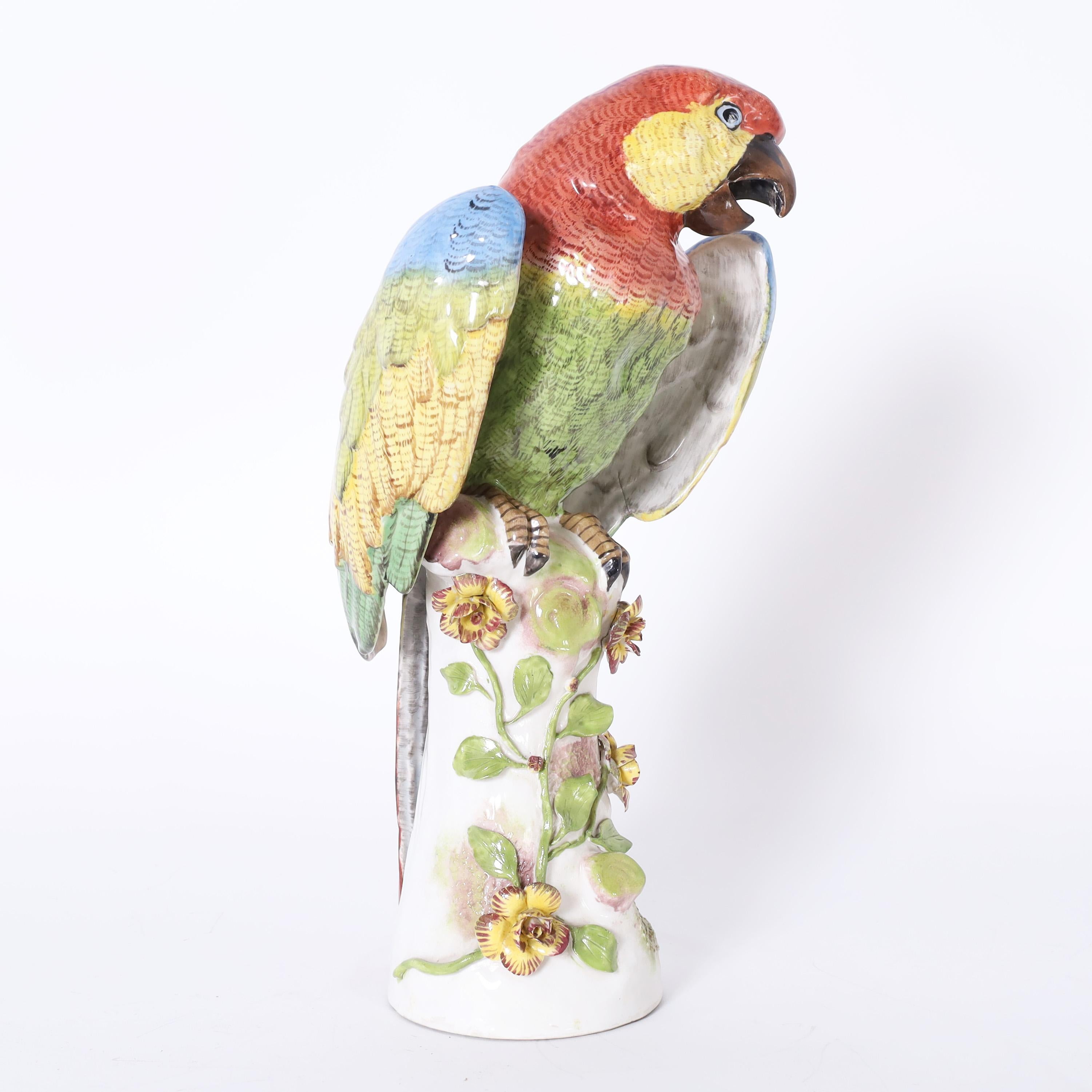 Lofty life size porcelain parrot hand decorated in vivid tropical colors, glazed and perched on a tree trunk. Signed with crossed arrows on the back. 