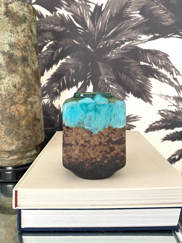 1960's handmade stoneware pottery vase from East Germany. The vase features a two-tone drip glaze along the top in moss green and turquoise. The lower portion of the vase has a matte stoneware finish in muddled hues of brown. The vase is marked on