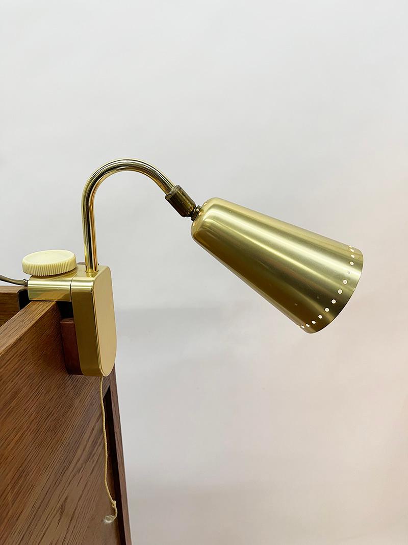 German reading lamp by Erco, 1950s

A German reading lamp with adjustable bracket in a brass-colored aluminum conical shaped lampshade, perforated with small round holes attached to a brass curved rod. Painted white inside. The lamp holder is